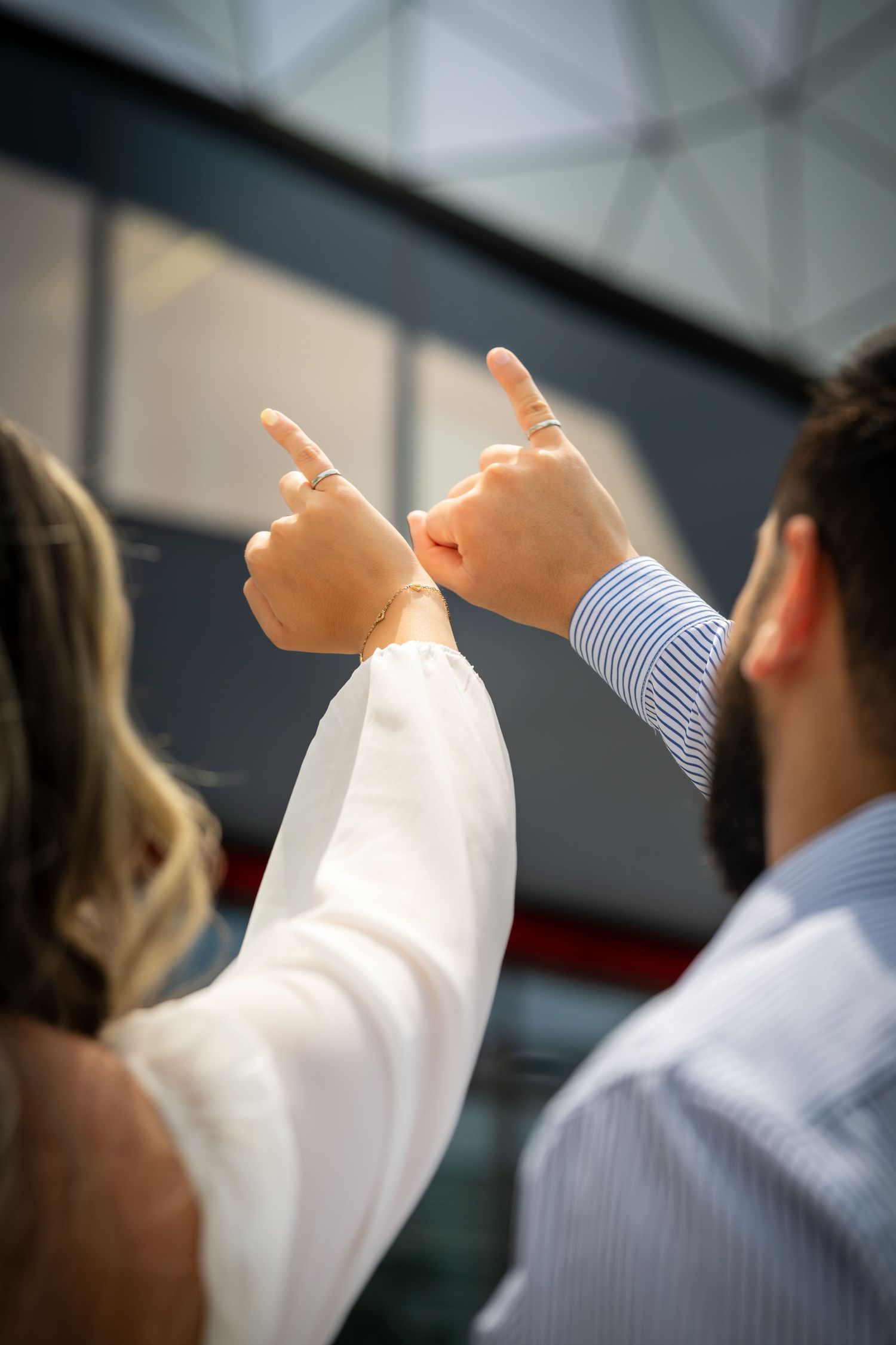 Two people point toward the sky in a candid outdoor moment.