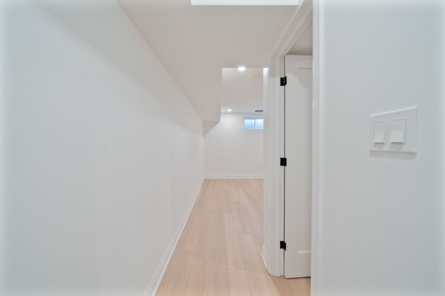 Modern white hallway with minimalist design features clean lines, pale wood flooring and recessed lighting.