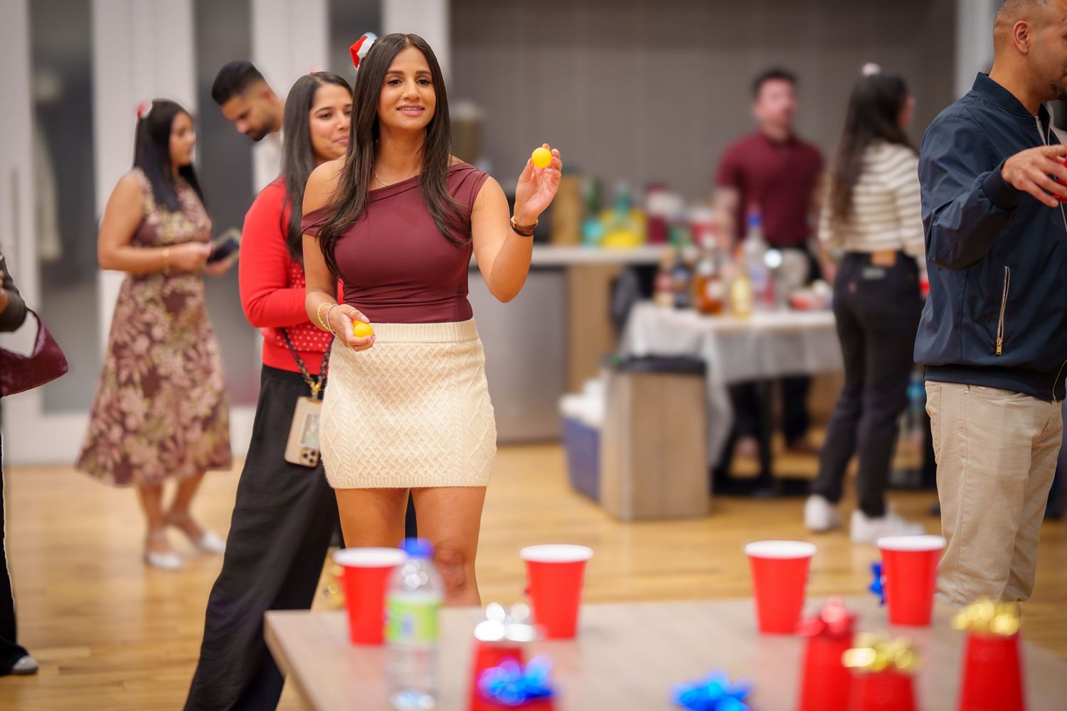 Red and blue plastic cups arranged on a wooden floor with party guests in the background.