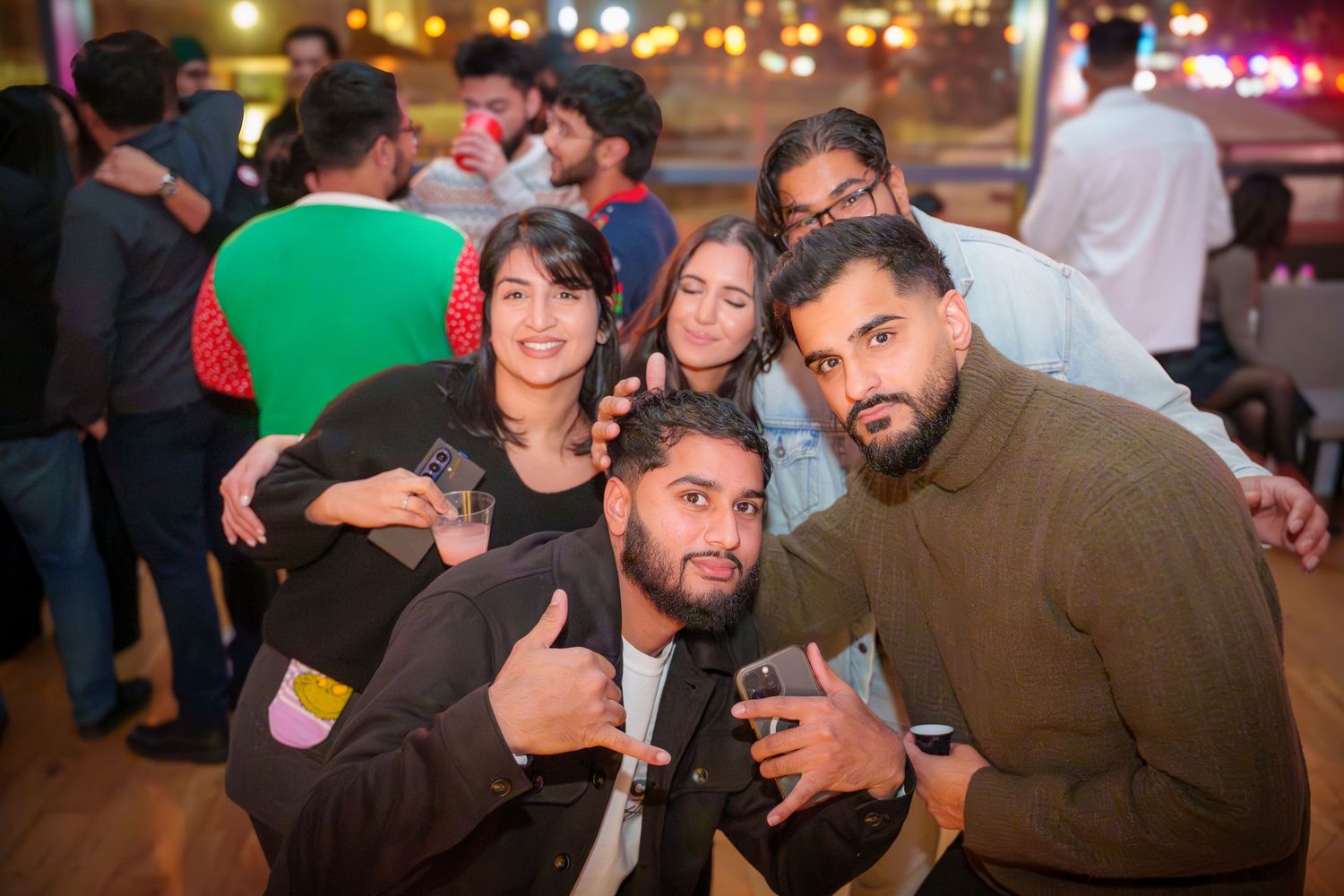 Party-goers celebrating and socializing in dimly lit indoor setting.