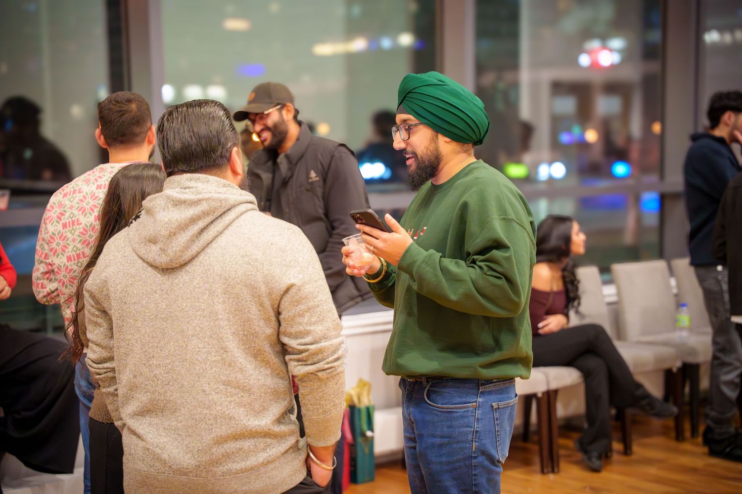 People socializing at an indoor gathering with drinks and casual attire.