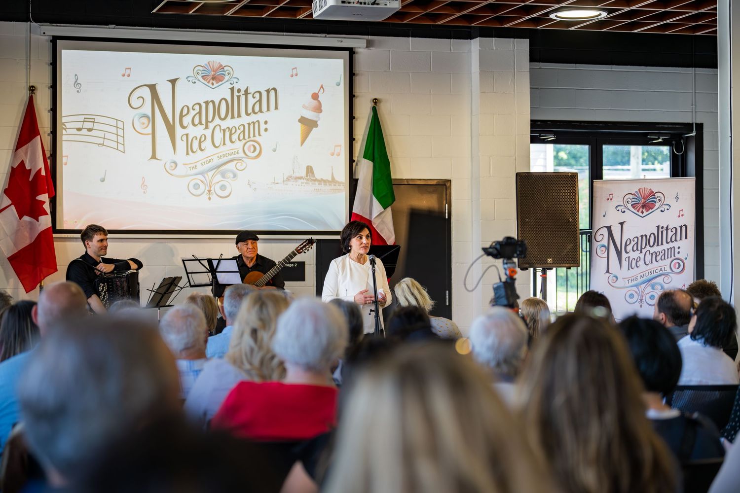 Musicians perform at a Neapolitan Ice Cream themed event with Italian and Canadian flags displayed on stage.