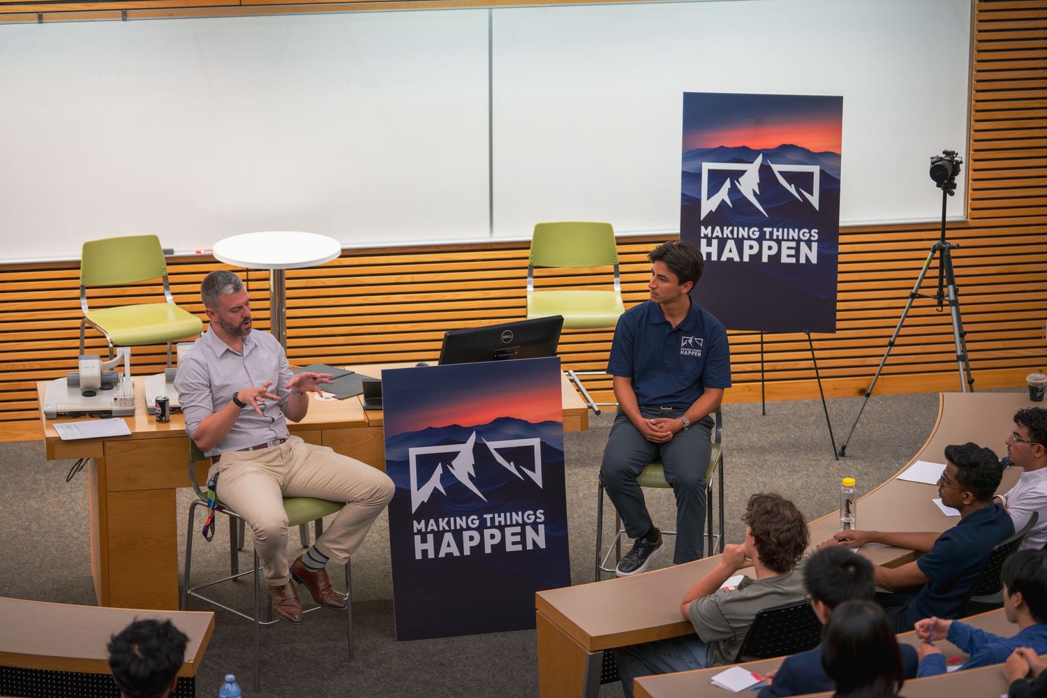 Wide view of lecture hall with presentation screen showing company branding.