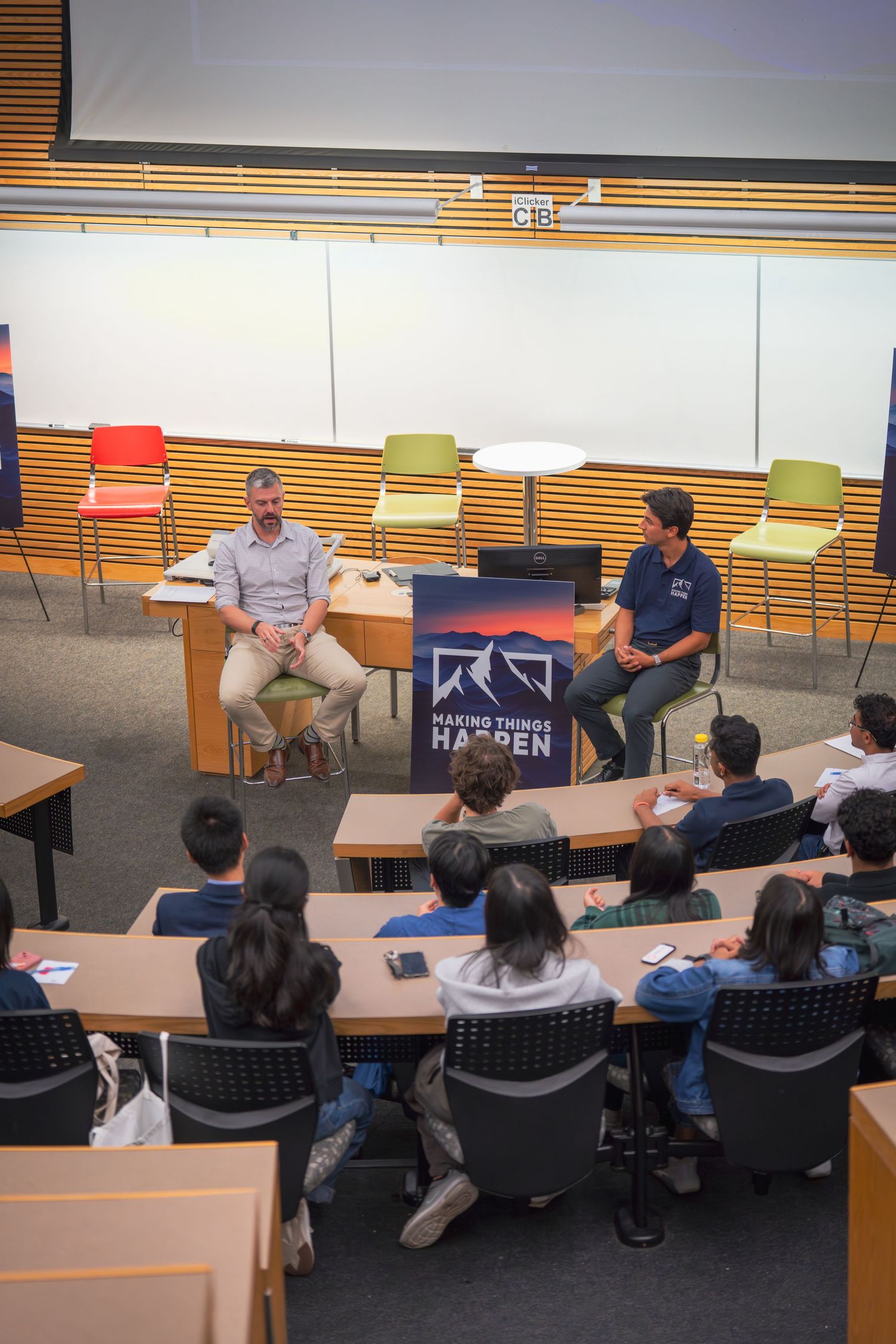 Wide view of a conference room with attendees seated around a large table during a presentation.