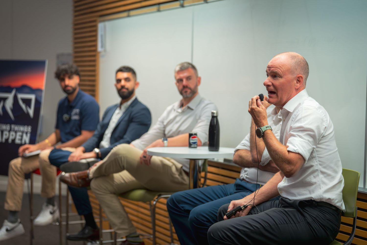 Professional panel discussion in modern conference room with wooden wall accents.