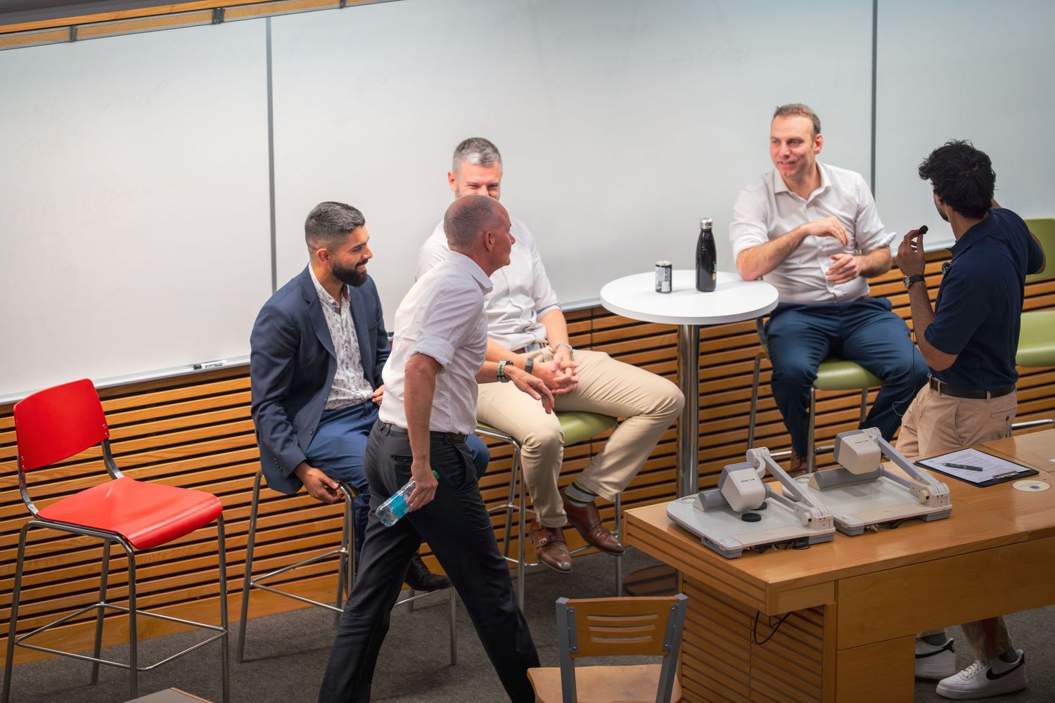 Group discussion in progress within modern conference space with wood accent walls.