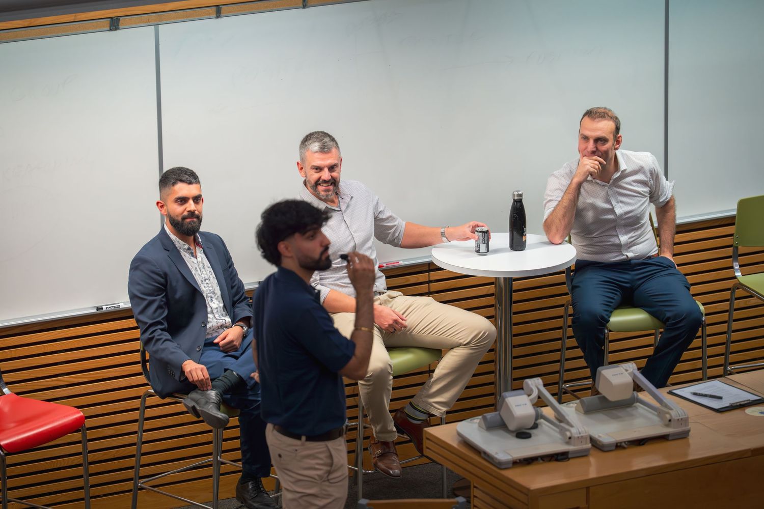 Business professionals engage in conversation around a modern conference table.