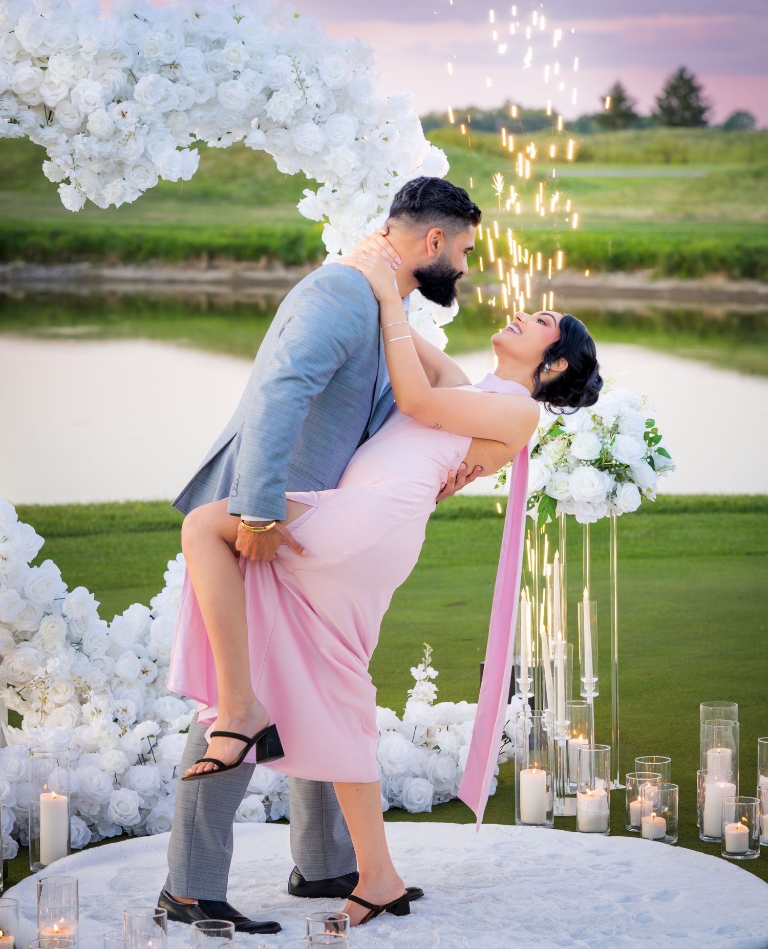 A romantic dip pose captured at sunset with white floral arrangements and glowing candles.