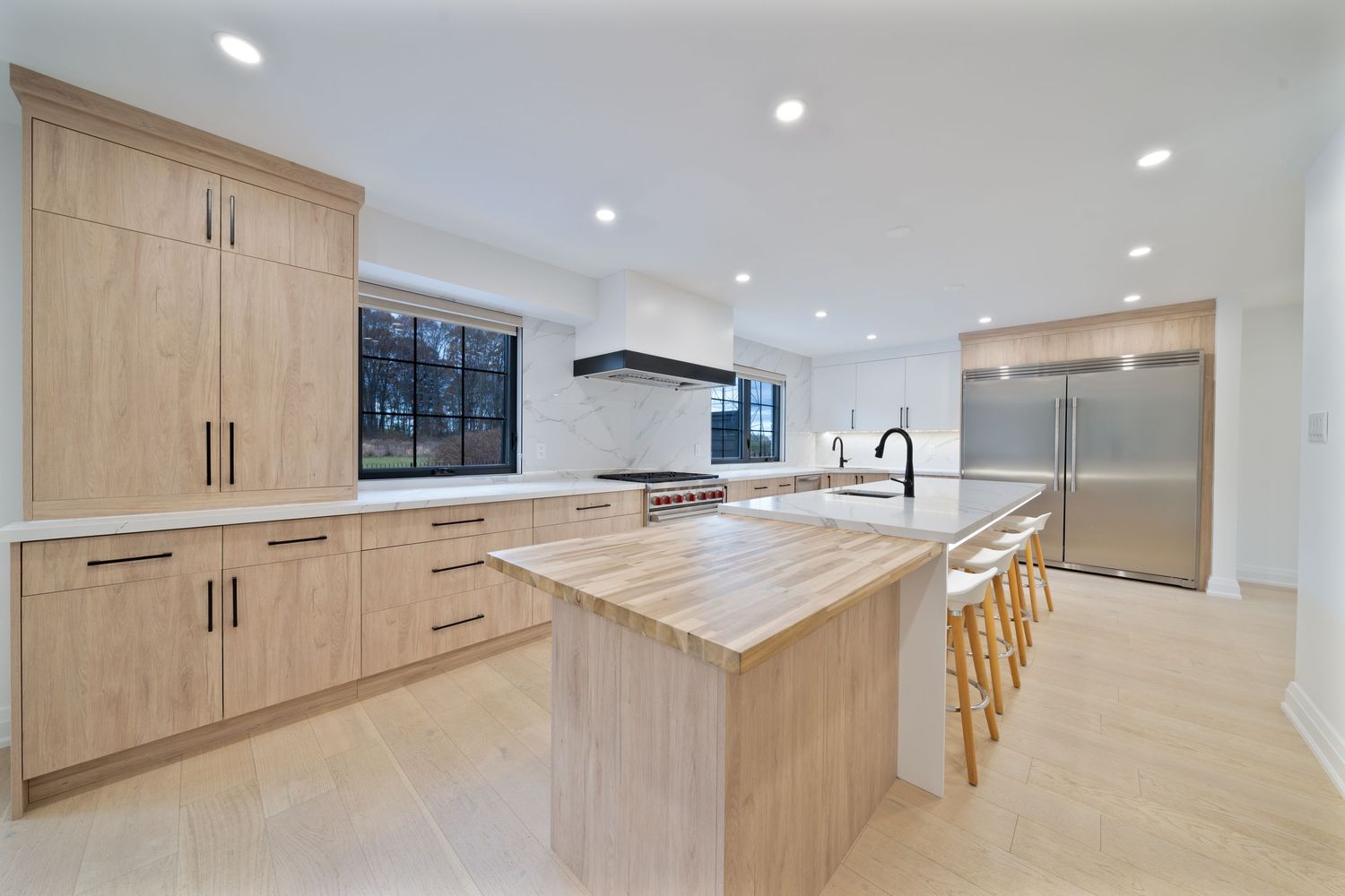 Modern basement renovation with light wood cabinets and recessed lighting showcases an open concept design.