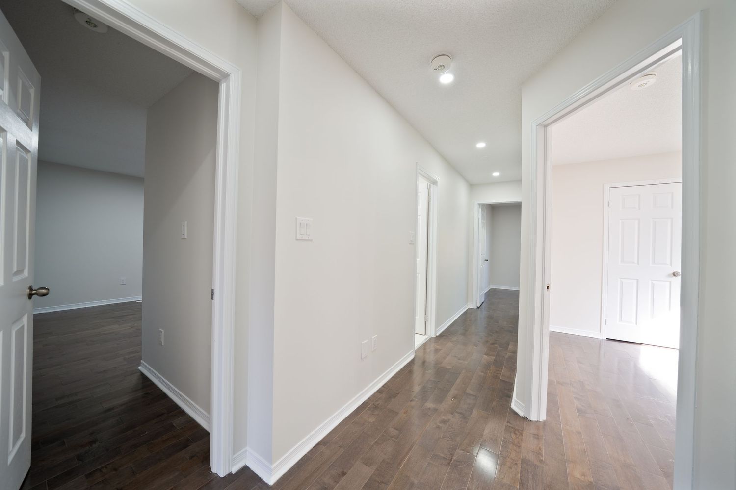 Interior view of a modern hallway with white walls and recessed lighting stretching into the distance.