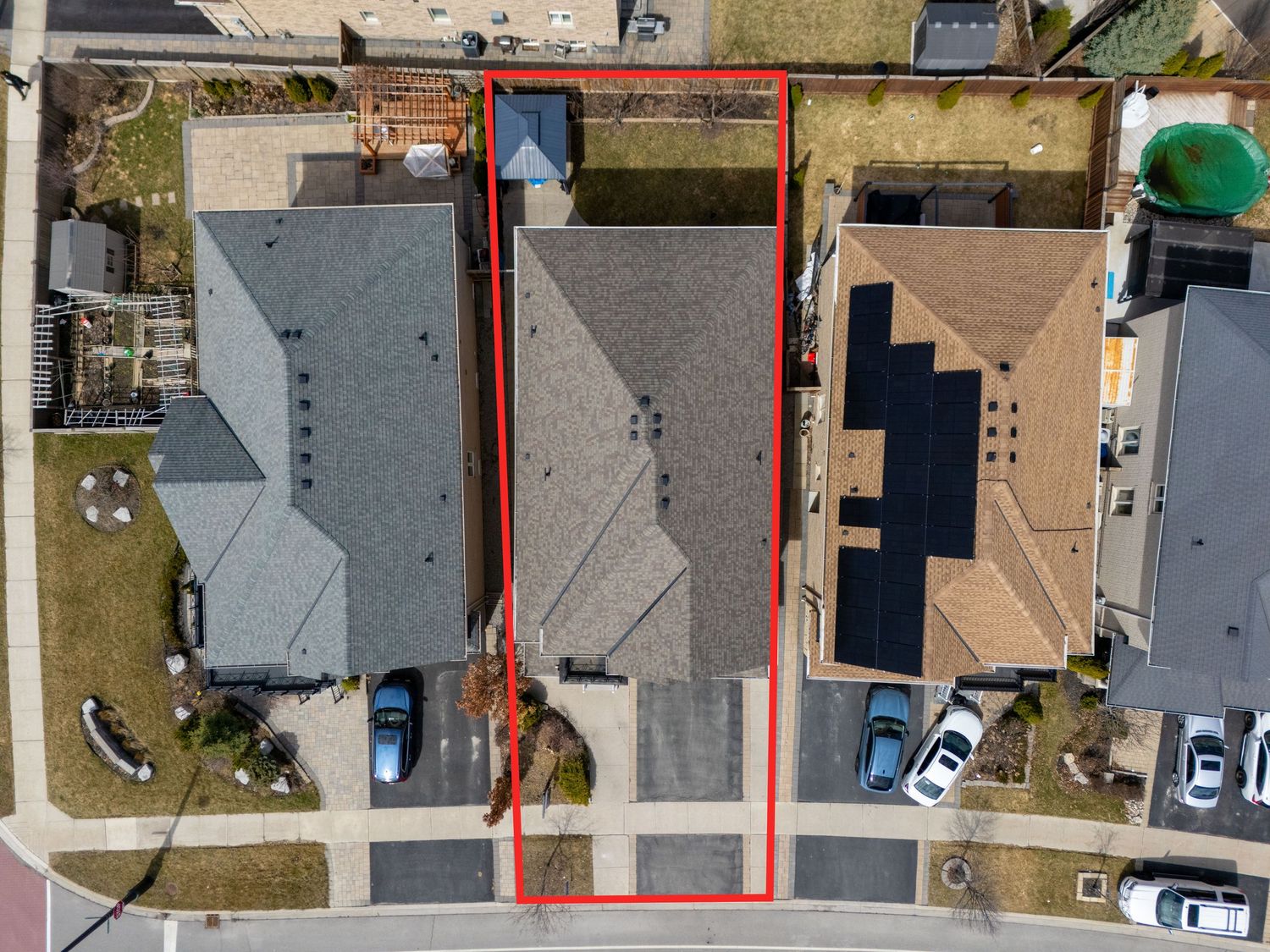Aerial view of residential neighborhood showing rooftops, driveways and parked cars from above.