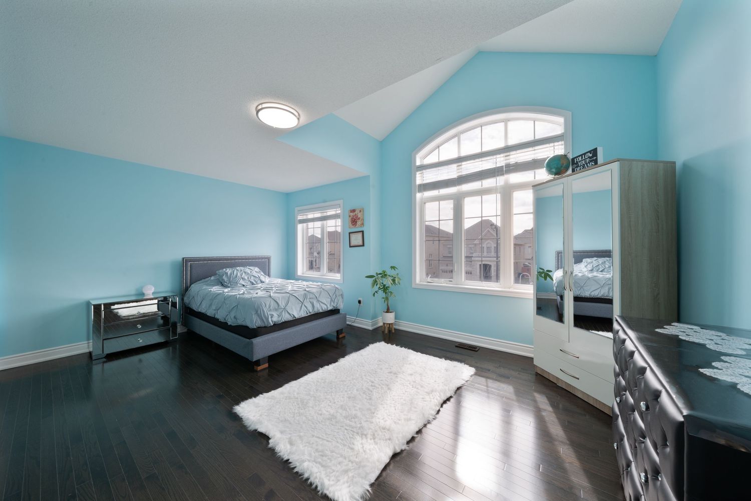 Modern bedroom interior with turquoise walls, recessed lighting, and white bedding in a minimalist design style.