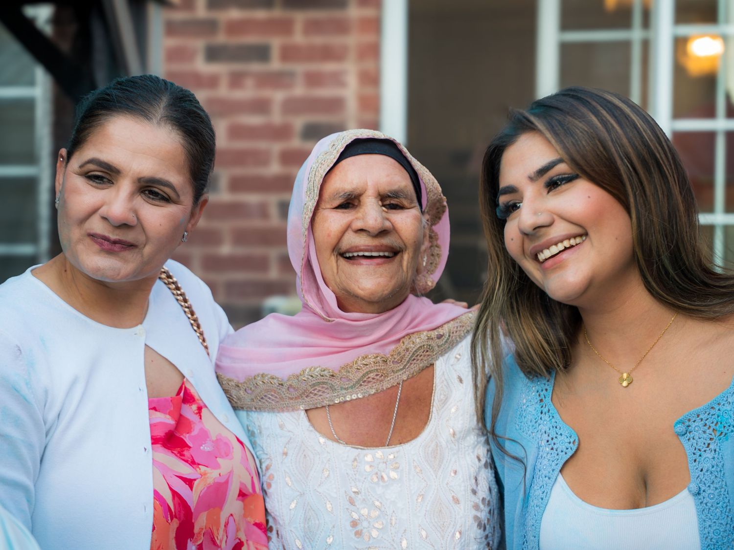 Three generations of women smiling together at a family celebration outdoors.