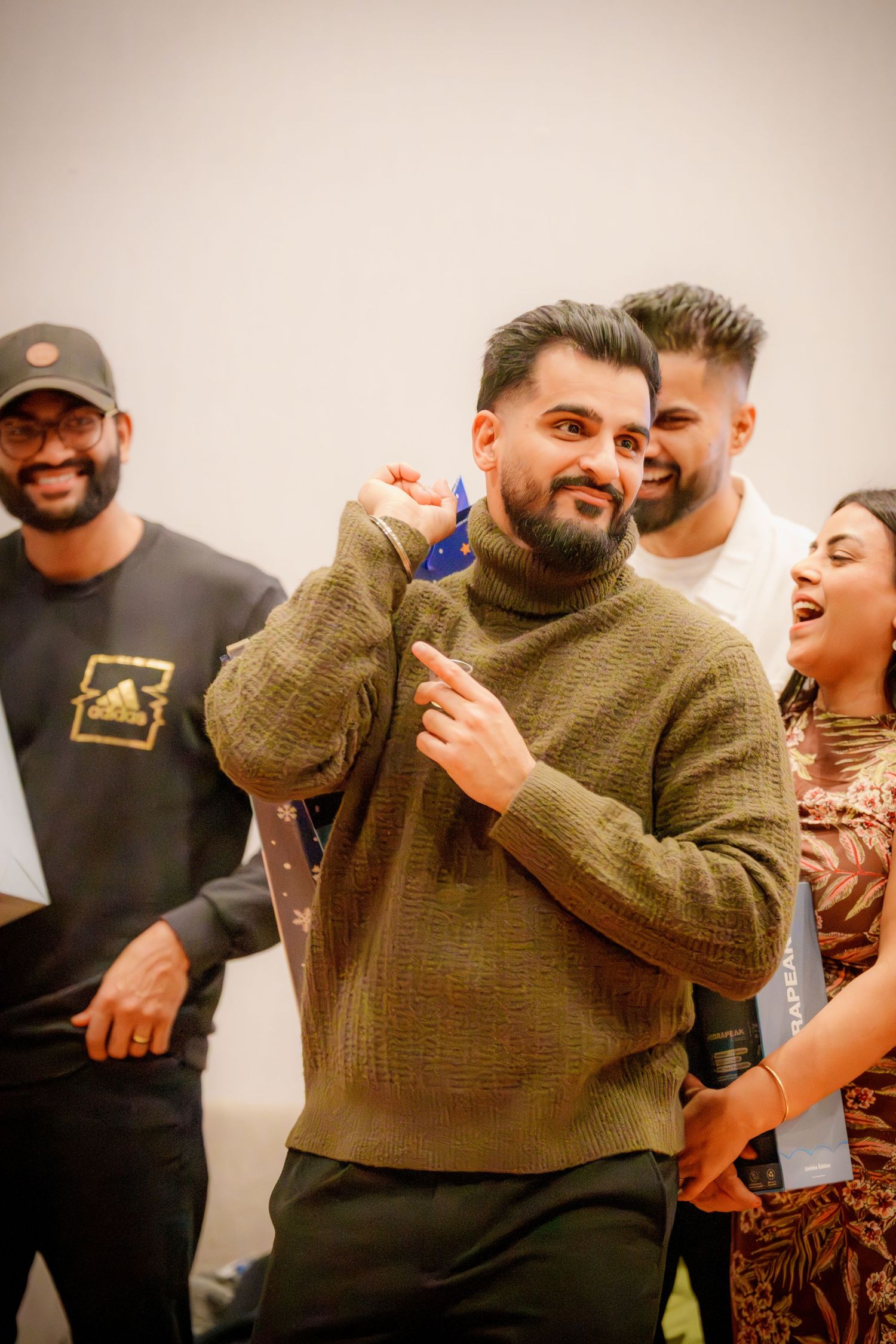 People enjoying themselves at an indoor party with someone in a brown sweater in focus.