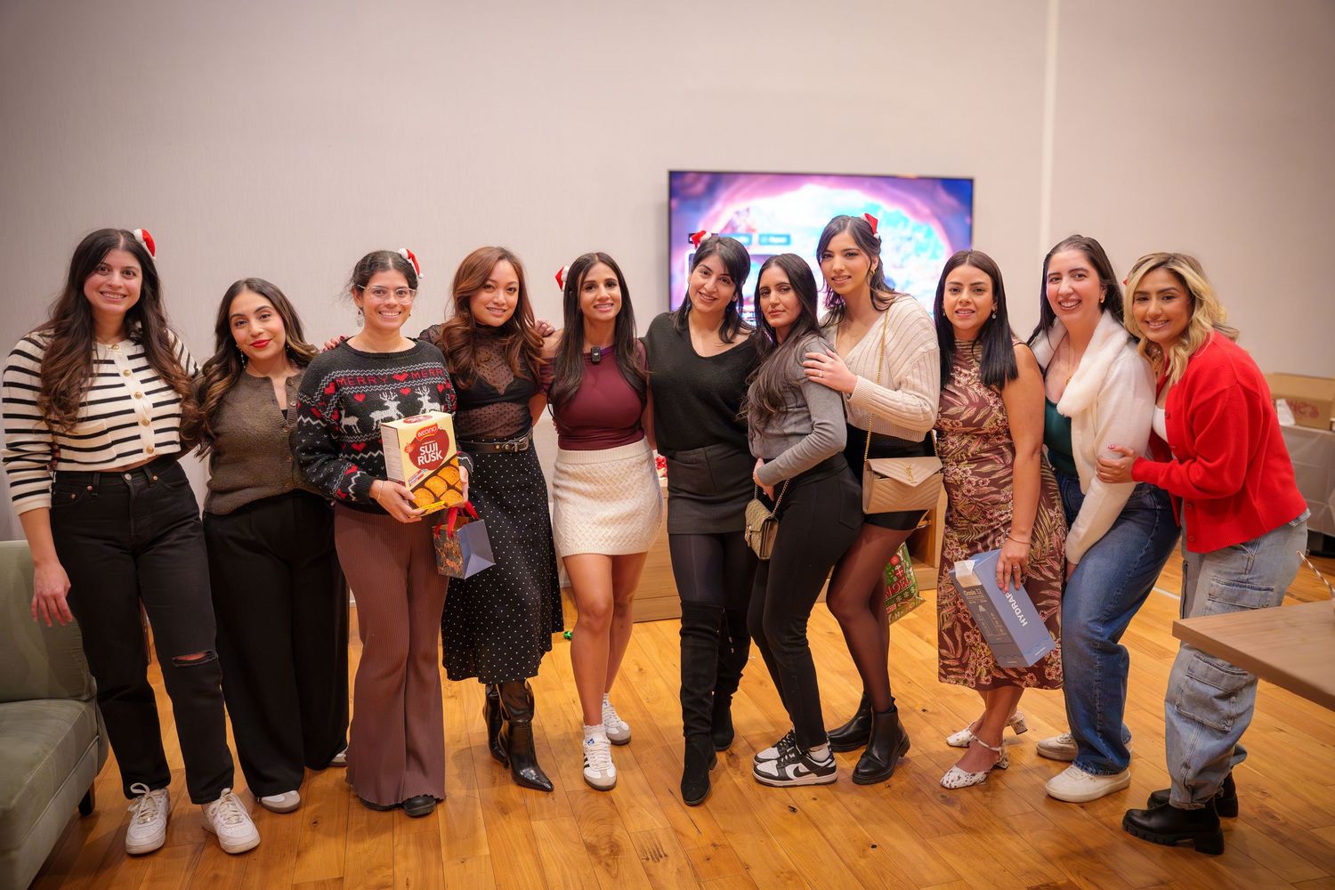 Group photo of friends at a party posing together in casual attire against a gray wall.