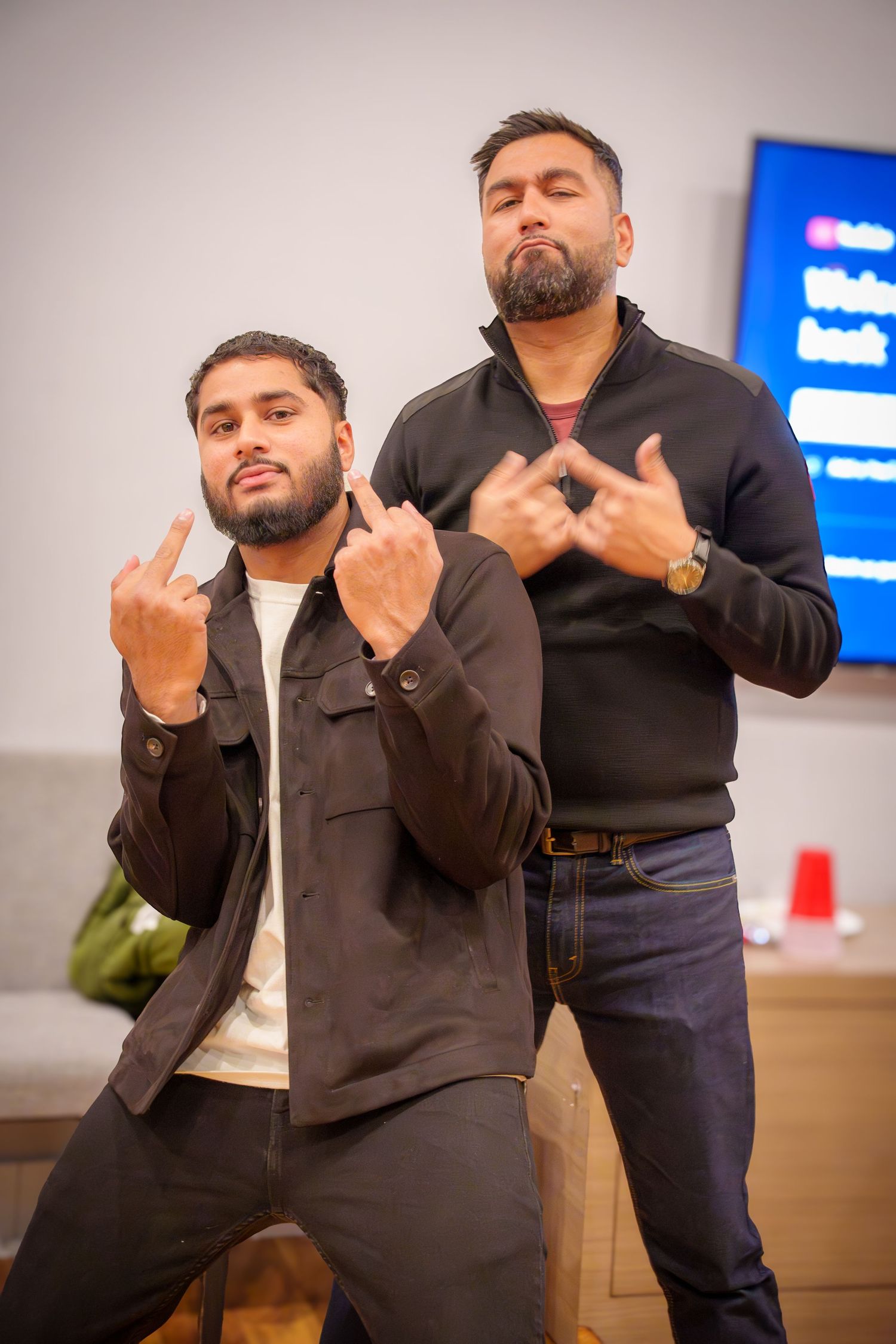 Person in dark jacket making hand gestures during indoor event.