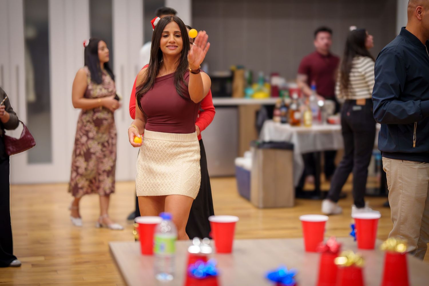 People gathered around tables with red cups at an indoor social event.