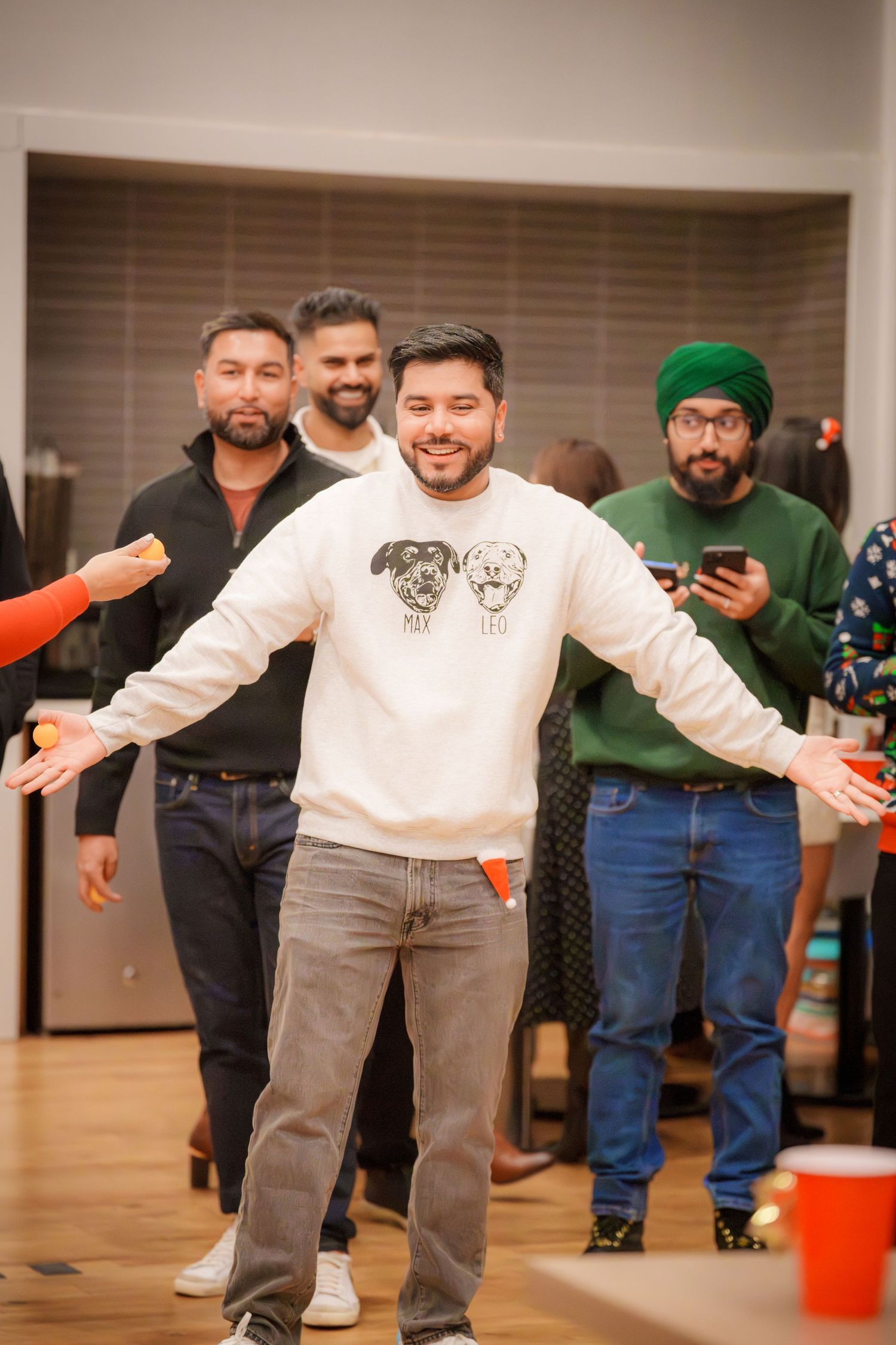 People dancing and having fun at an indoor party with arms outstretched in a playful pose.