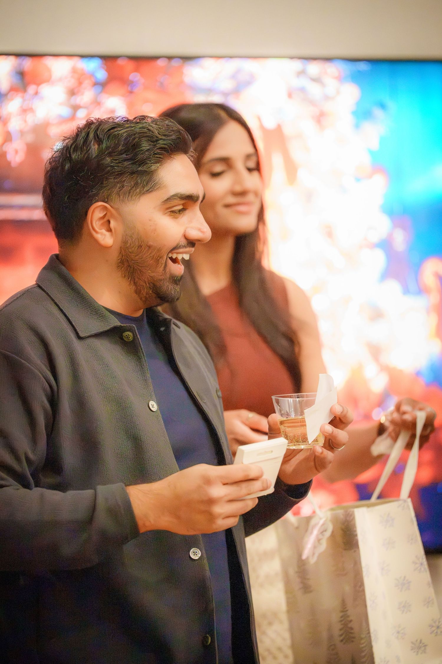 Person holding a drink and smiling at a party with colorful lighting effects.
