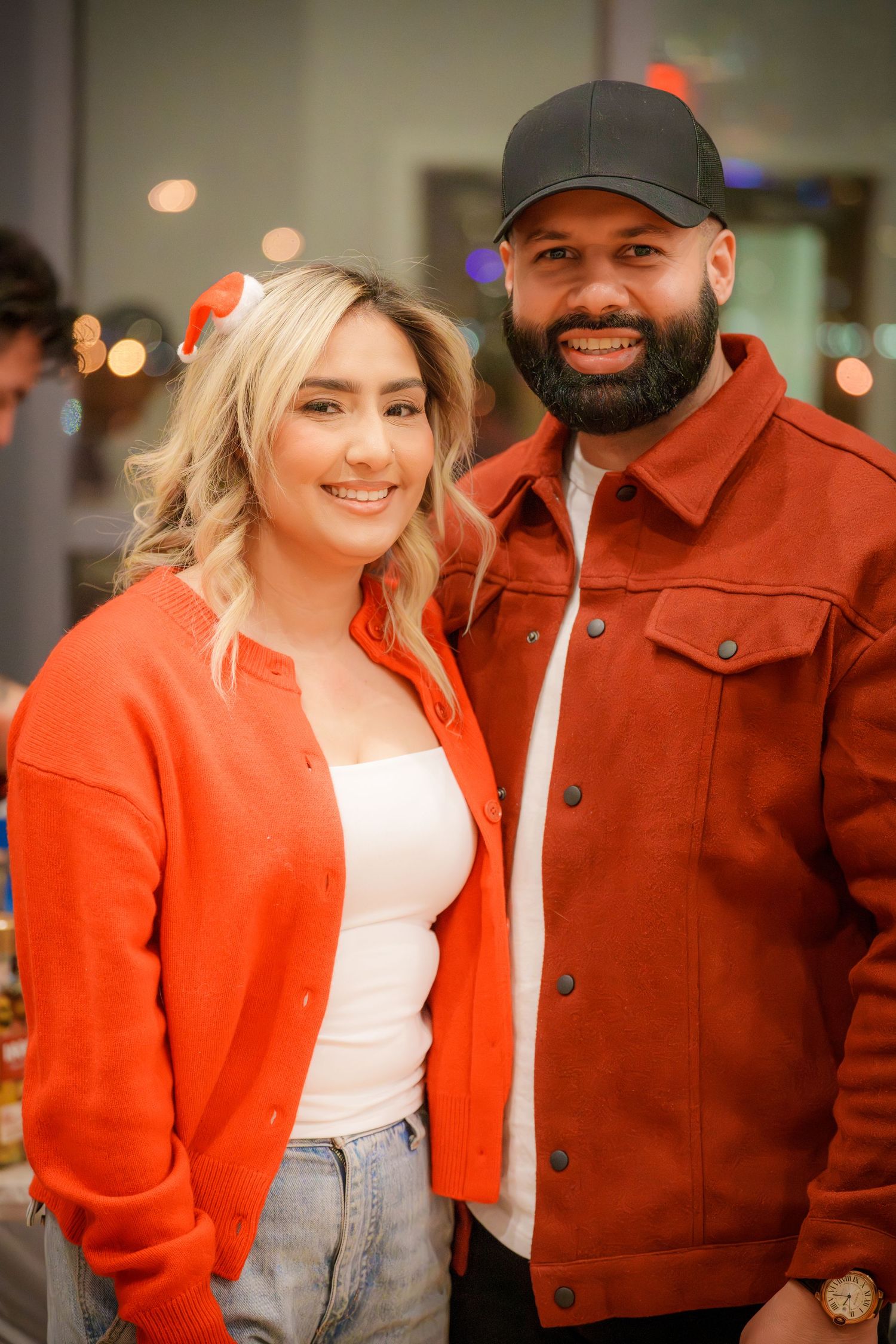 A couple in casual attire smiling together at a social gathering.