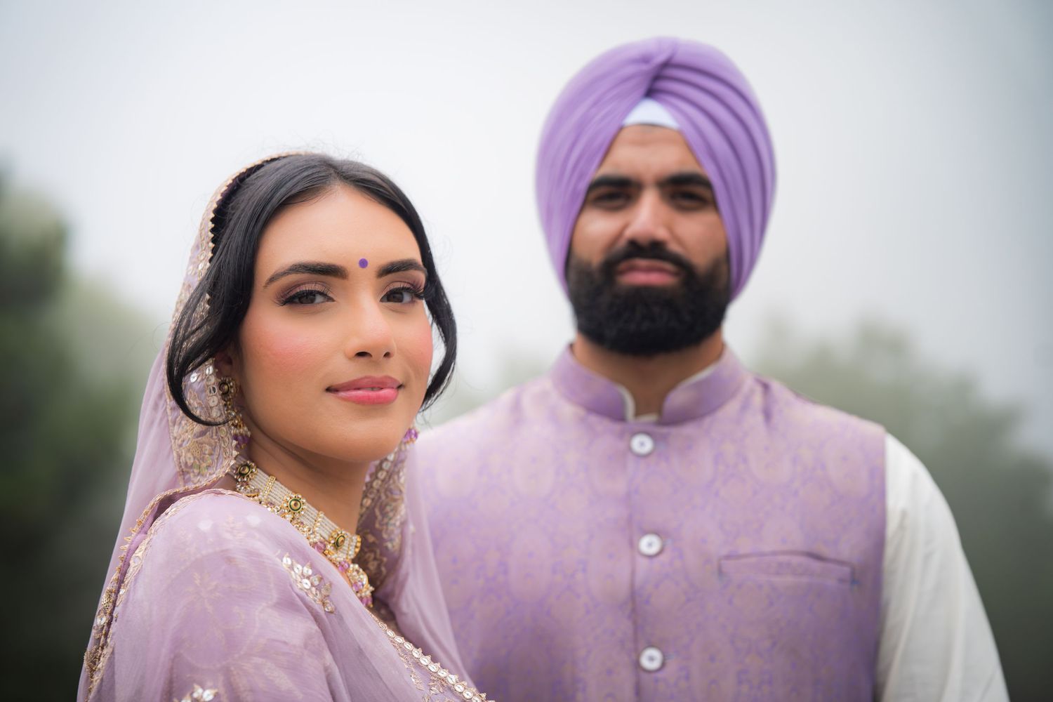 Romantic outdoor wedding portraits in coordinated purple and white traditional Indian attire.