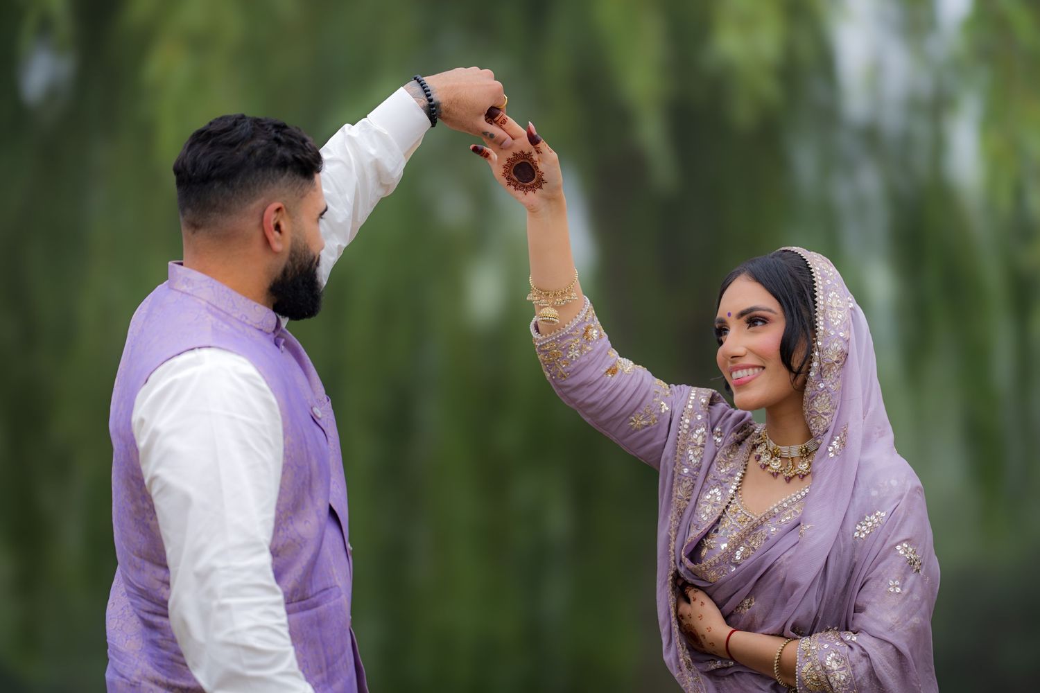 A romantic dance pose between a couple wearing coordinated purple and white traditional outfits.