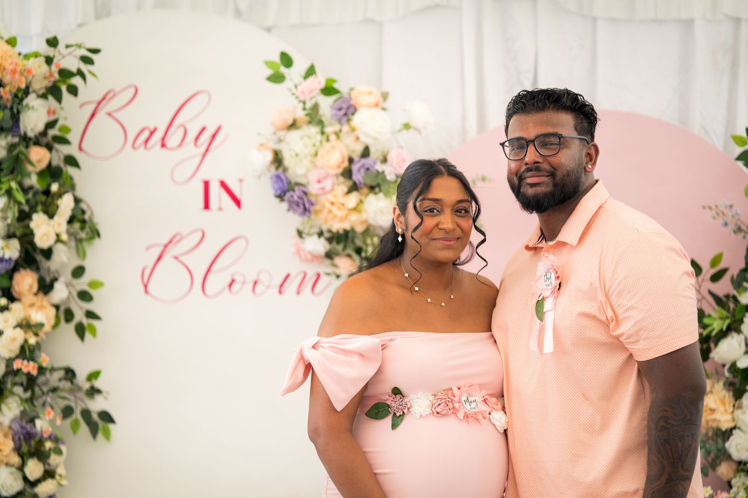 Celebration setup with pink theme, floral arrangements and white fabric backdrop.