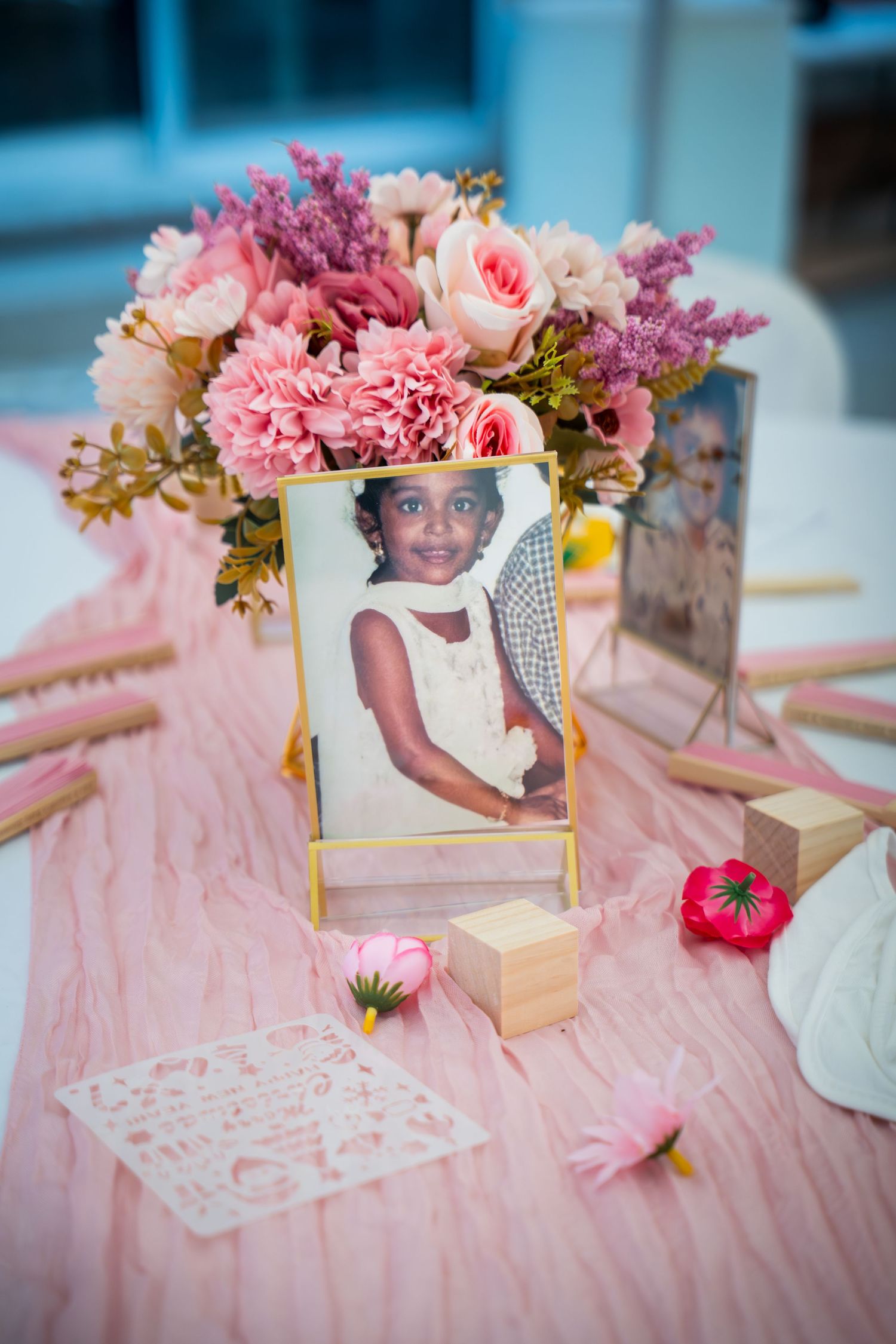Pink themed baby shower table with floral arrangements and vintage photo displays.