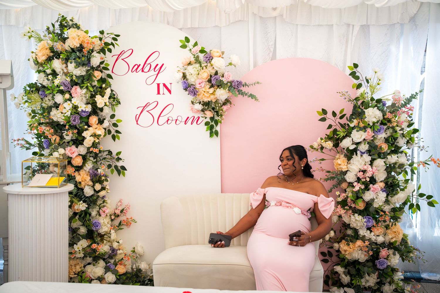 Baby shower decorations featuring pink signage and floral arrangements.