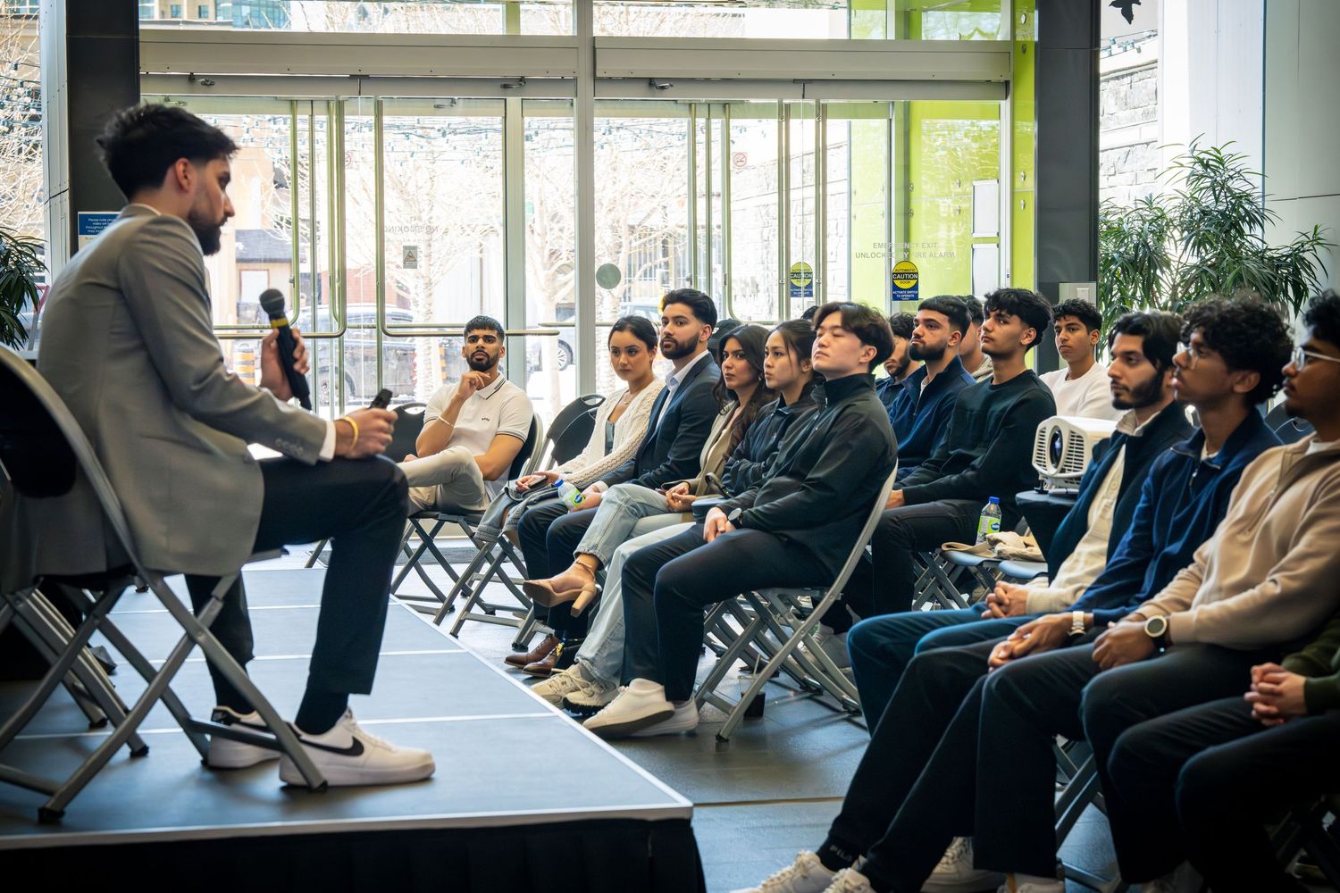 Wide shot of business conference showing speaker and attentive audience in modern venue.
