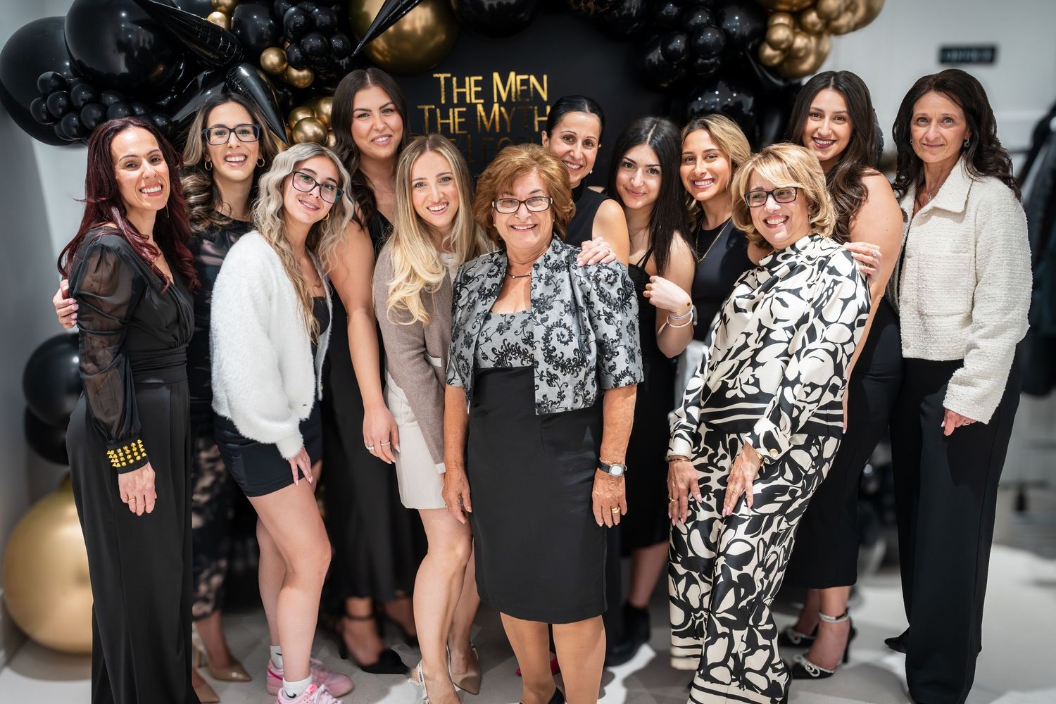 Celebration gathering with multiple guests posing in front of elegant balloon display.