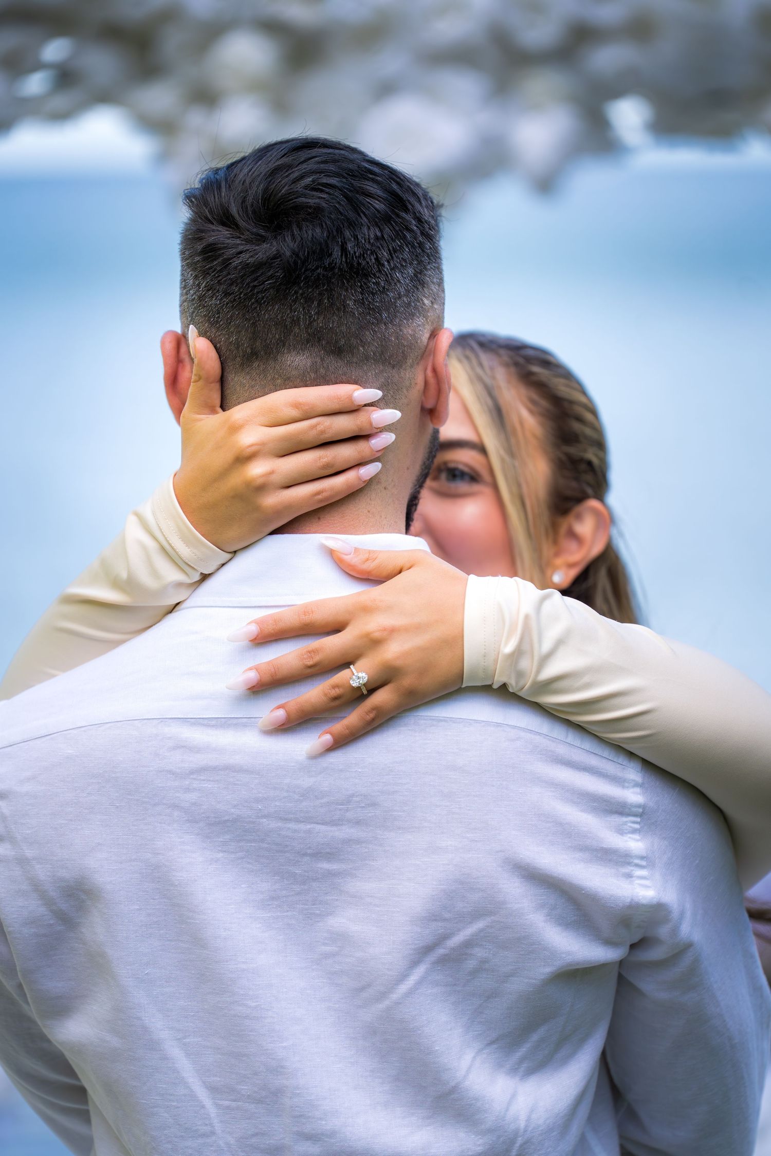 Tender moment between newlyweds showing wedding ring during outdoor photo session.