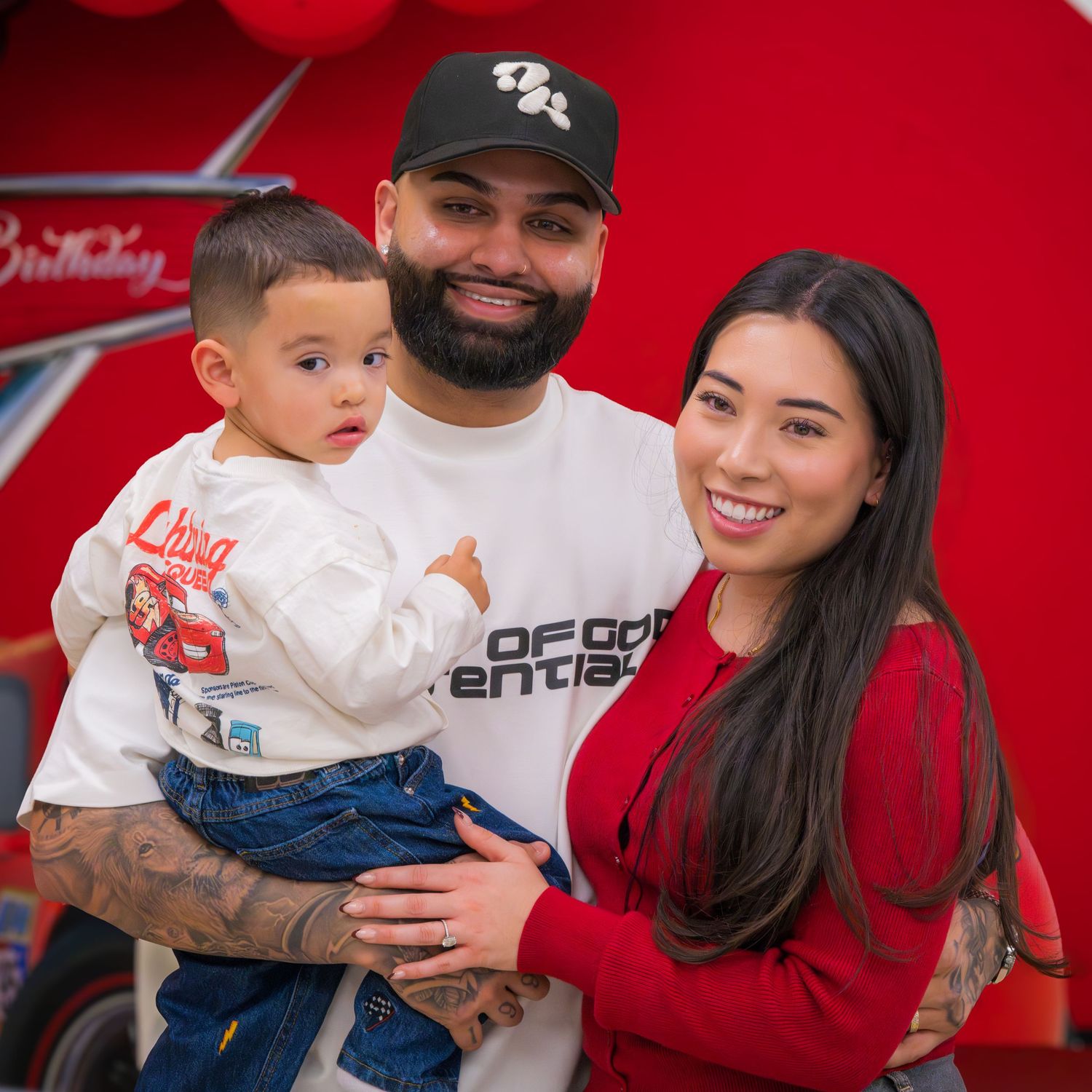 Family portrait with father, mother in red, and toddler at Cars themed birthday party.