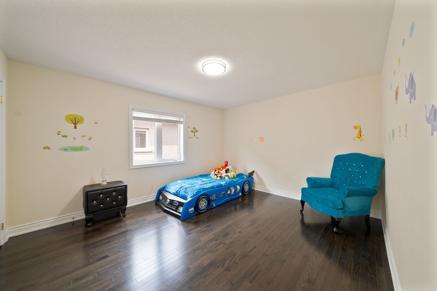 Panoramic view of a finished basement with beige walls, hardwood floors, and scattered blue furniture pieces.