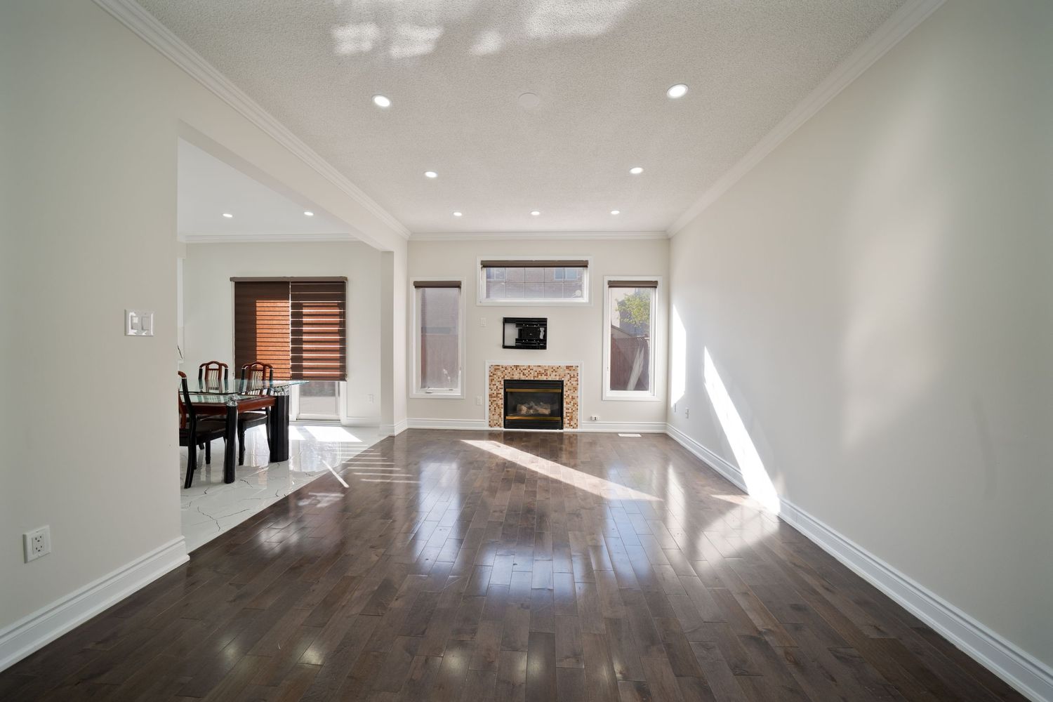 Empty white modern apartment interior with hardwood floors and natural light streaming through windows.