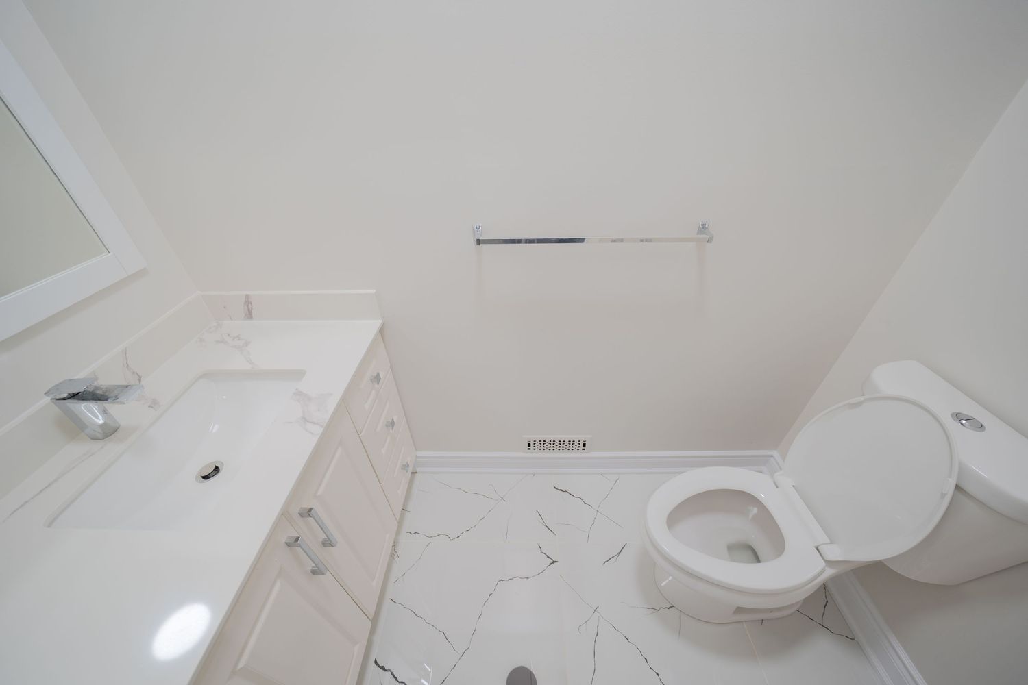 A modern white bathroom interior with toilet, sink, and tiled walls showing a clean minimalist design.