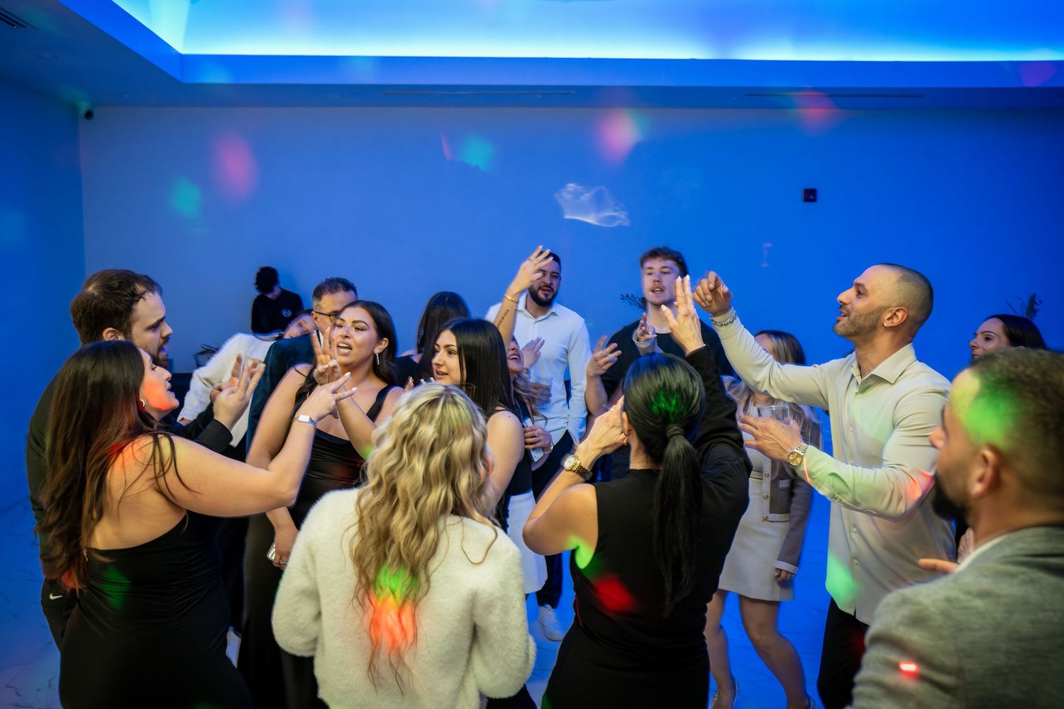 Dance floor filled with celebrating guests under atmospheric blue lighting.