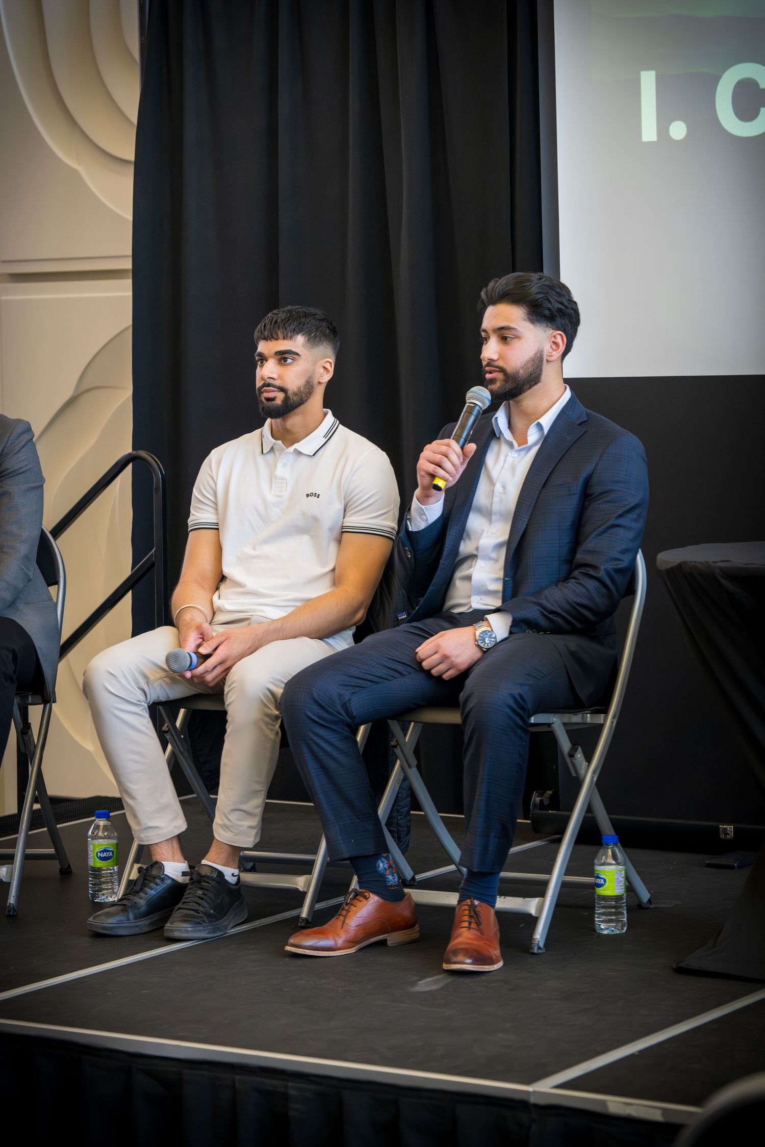 Professional panel discussion featuring speakers in contrasting formal and casual business wear.