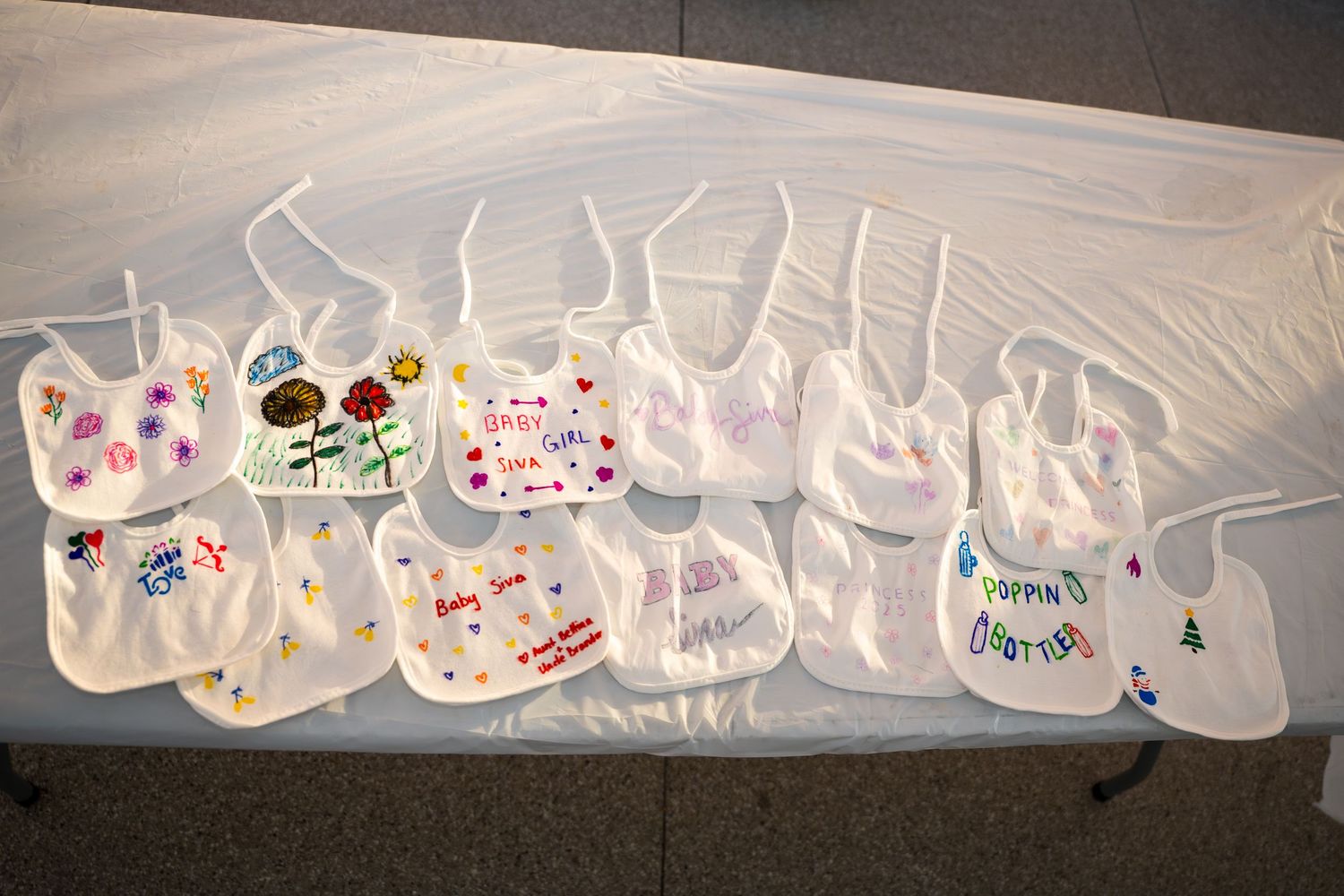 Panoramic view of multiple decorated baby bibs arranged in a continuous line.