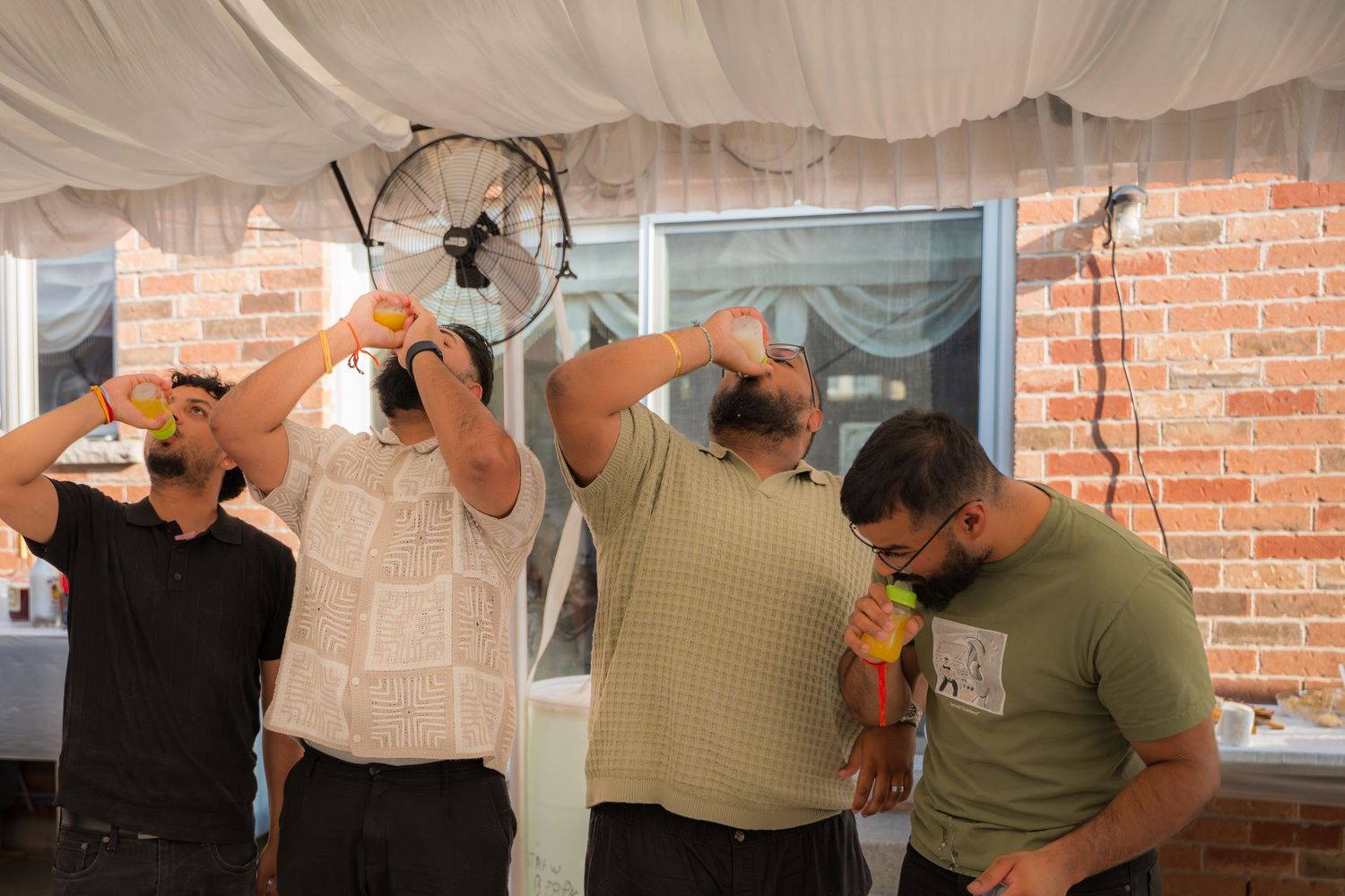 Group of people taking shots of drinks at an indoor event.