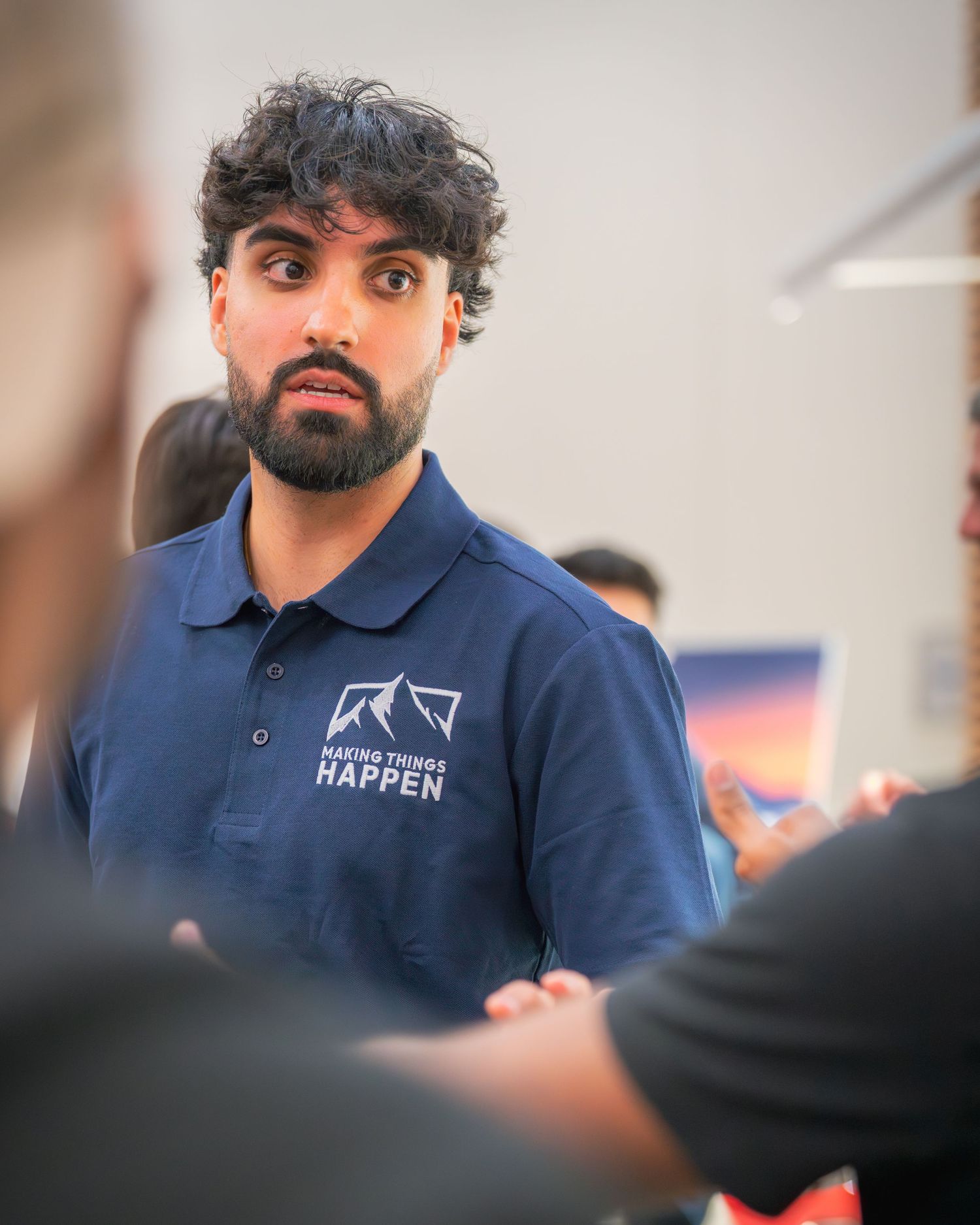 Conference participant in navy polo shirt engaged in discussion during breakout session.