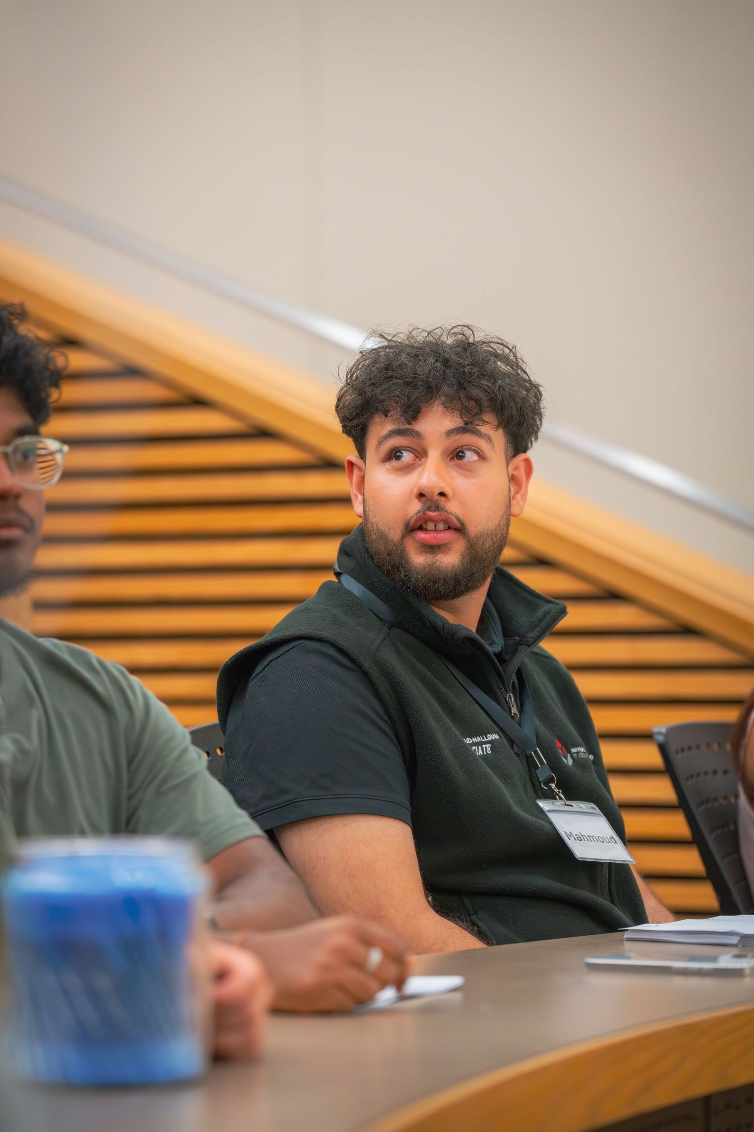 Student in a navy polo shirt attending a lecture in classroom setting.