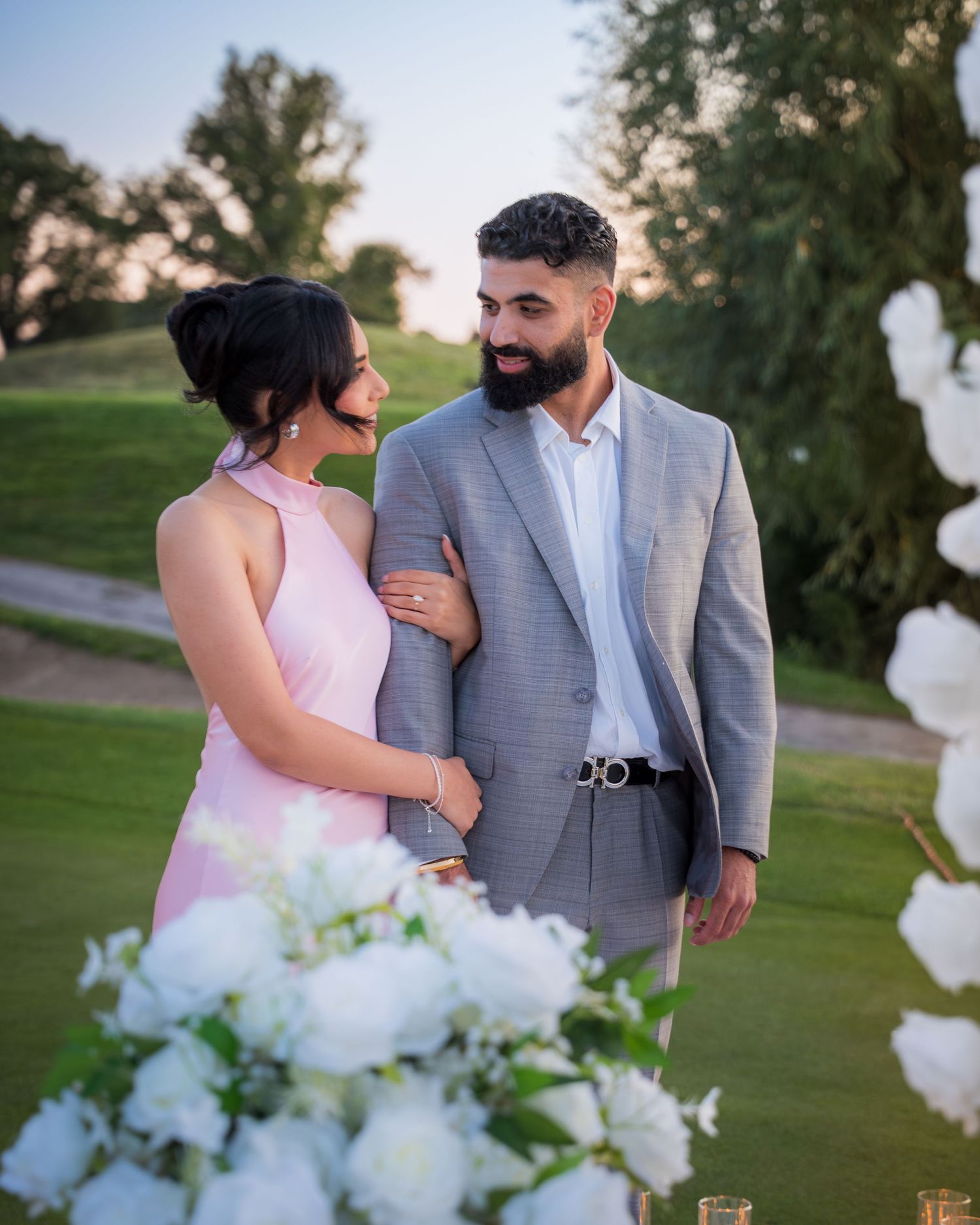 Romantic outdoor photoshoot on a golf course with elegant white floral arrangements.