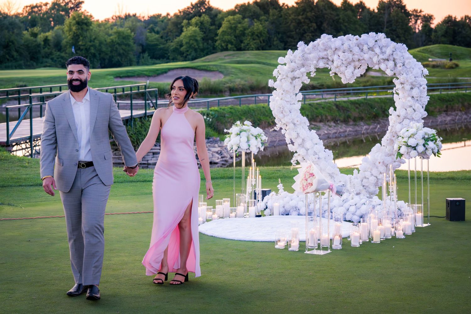 Wedding couple poses on golf course with elegant white balloon and floral decorations.