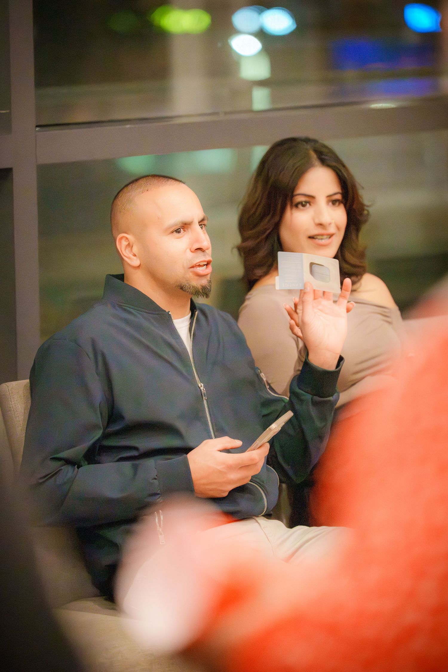 Party guests engaged in conversation with colorful lighting in the background.