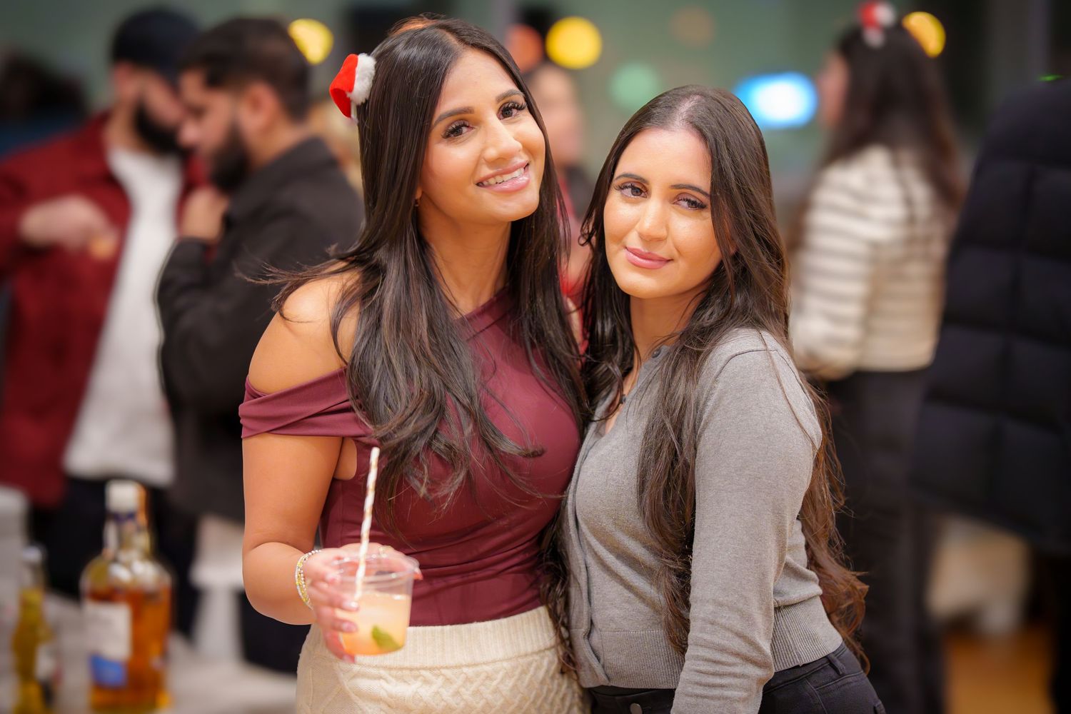 Friends socializing at an indoor party with festive lighting in background.