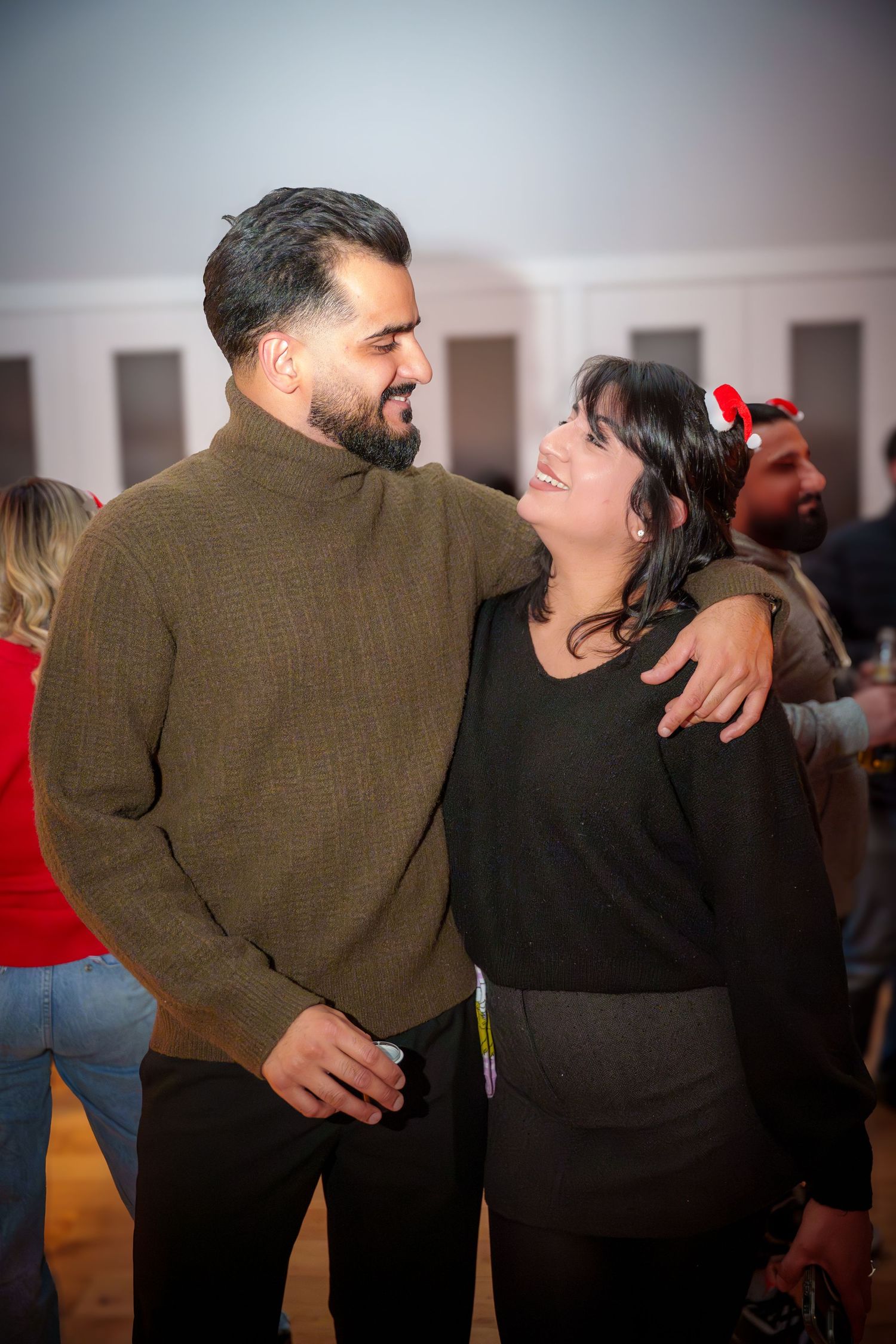 Two people share a laughing moment at an indoor social gathering.
