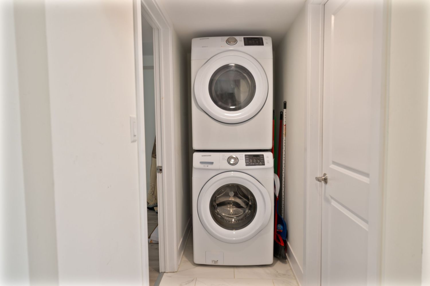 White laundry room with stacked washer and dryer units installed in a built-in alcove.