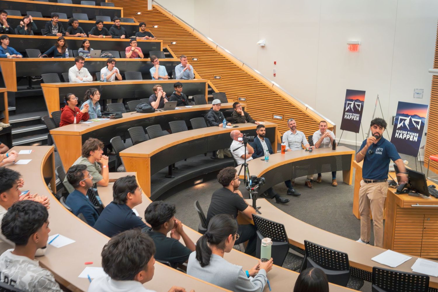 Students sit attentively in a lecture hall during an academic presentation or class discussion.