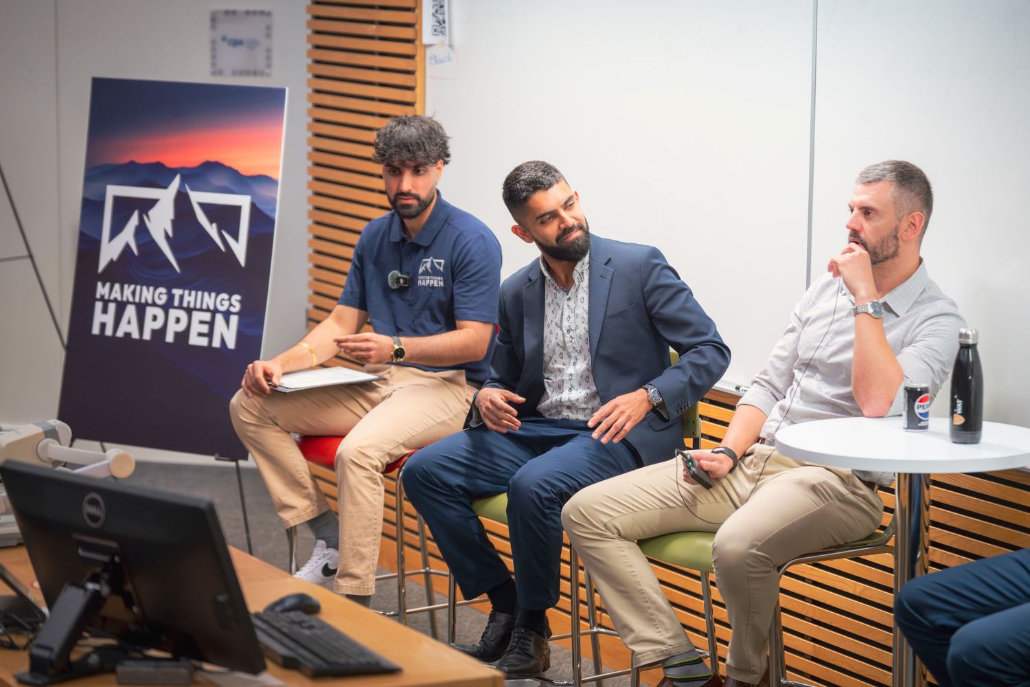 Presenters interact casually during panel discussion with branded backdrop.